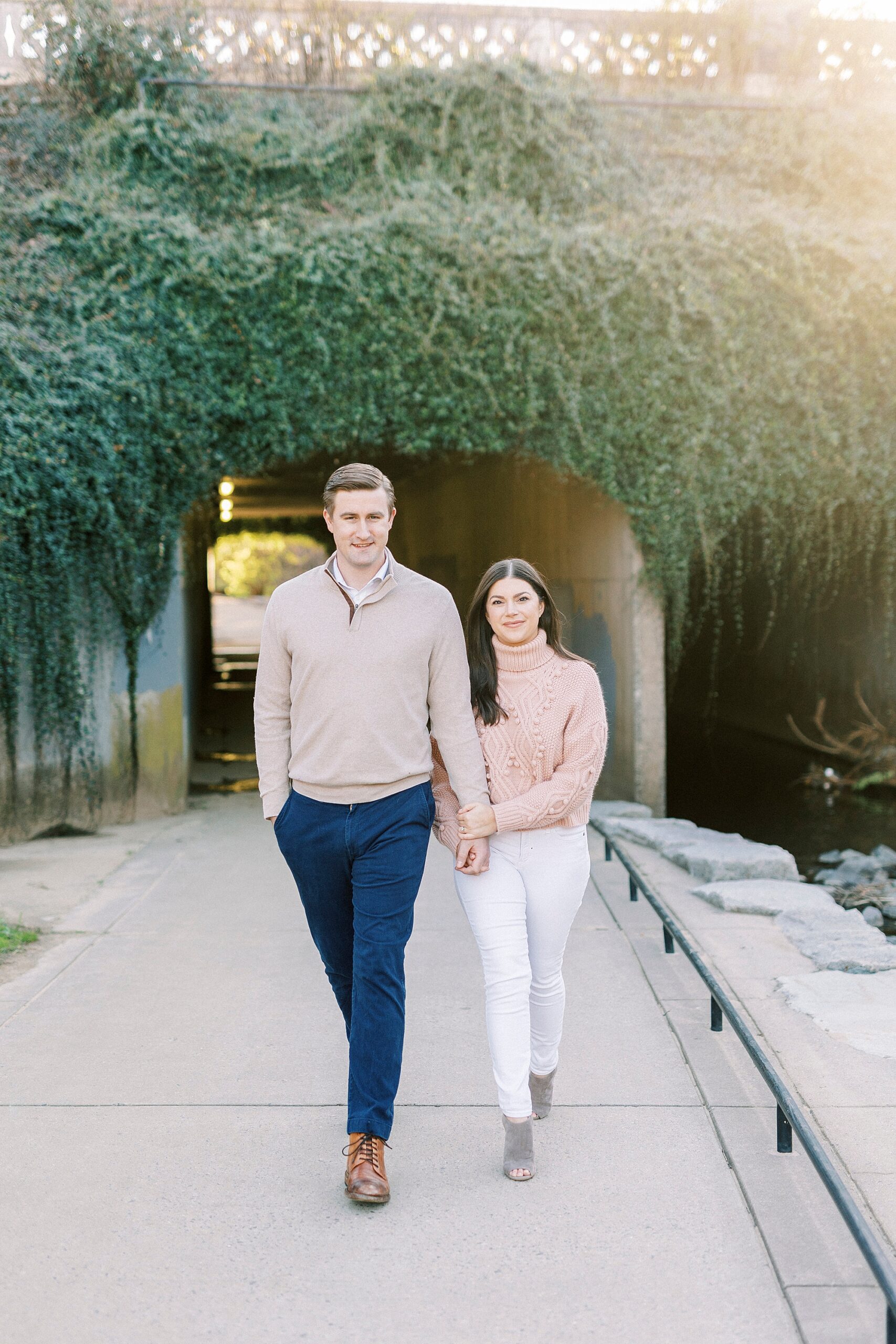 engaged couple walks together across pathway in park