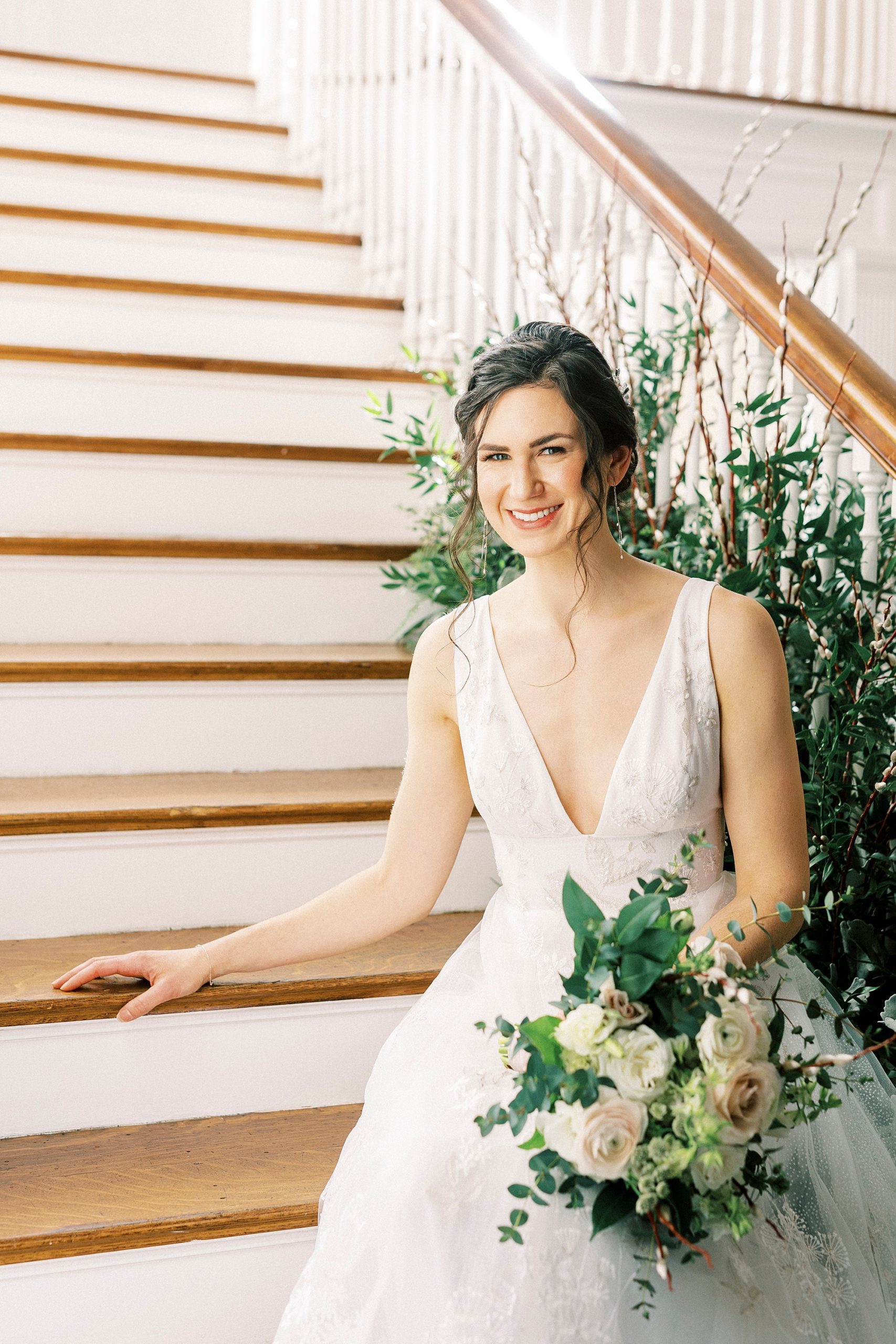 bride sits on steps at Separk Mansion with greenery along railing 