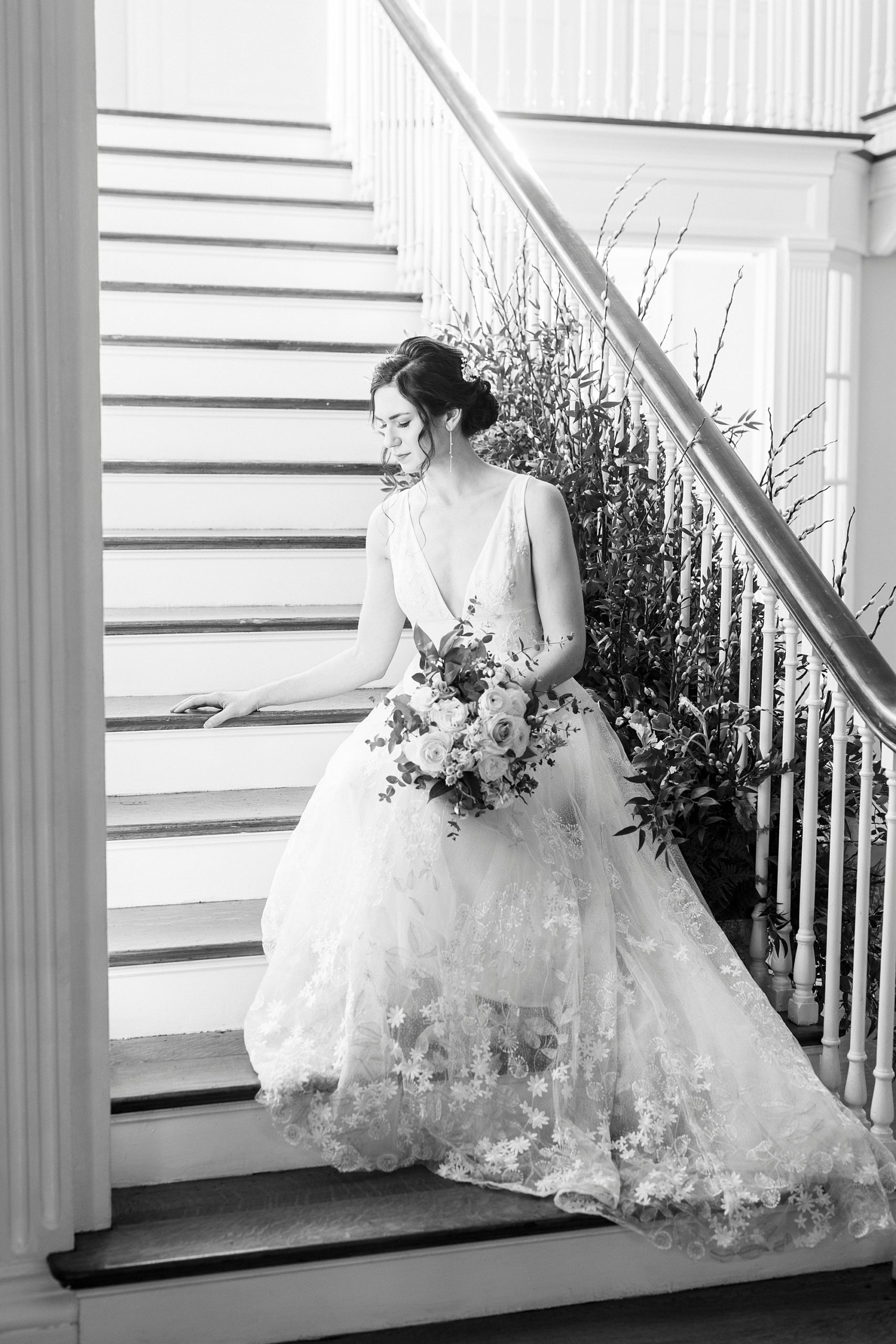 bride sits on steps at Separk Mansion holding bouquet with greenery behind her 
