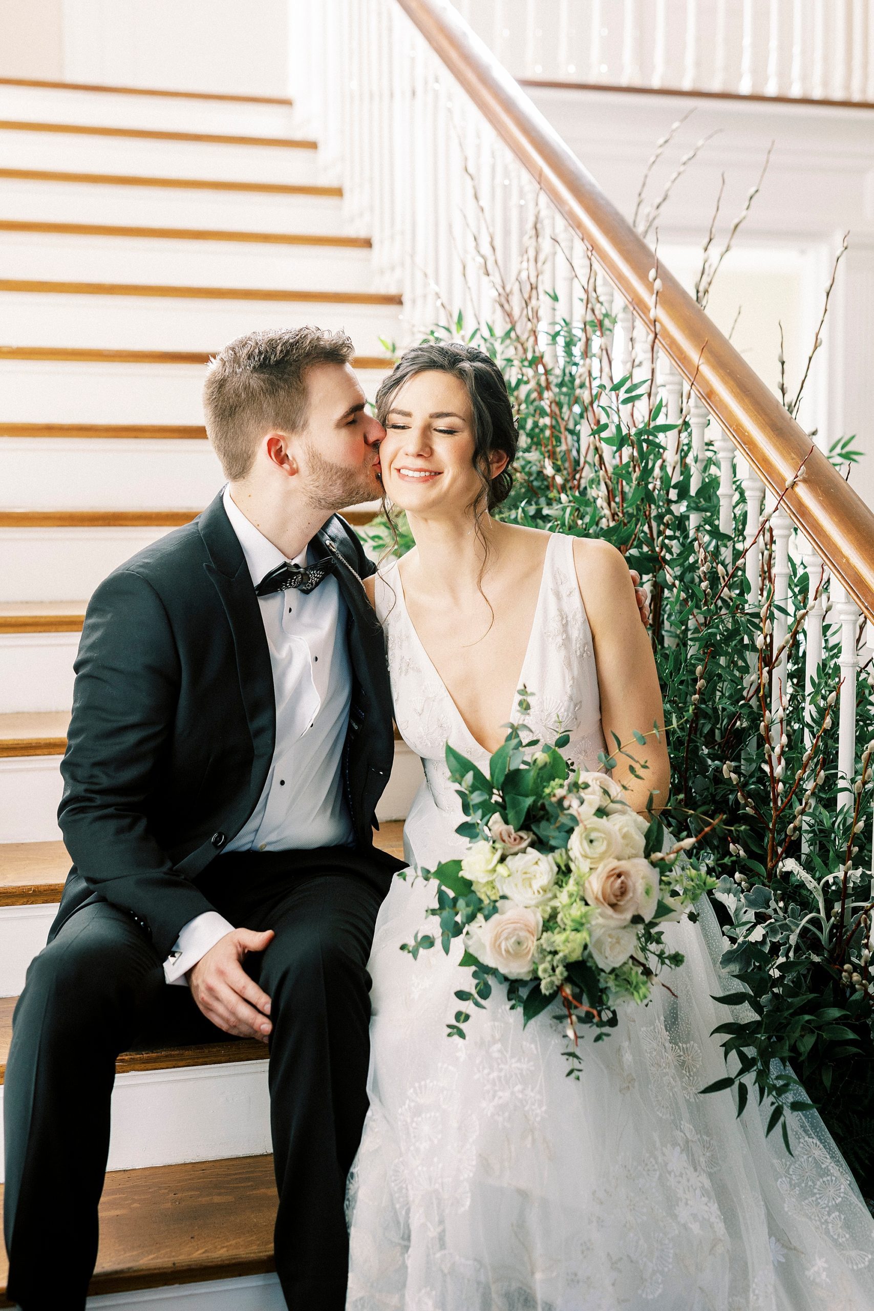 groom in tux kisses bride's cheek sitting on steps at Separk Mansion