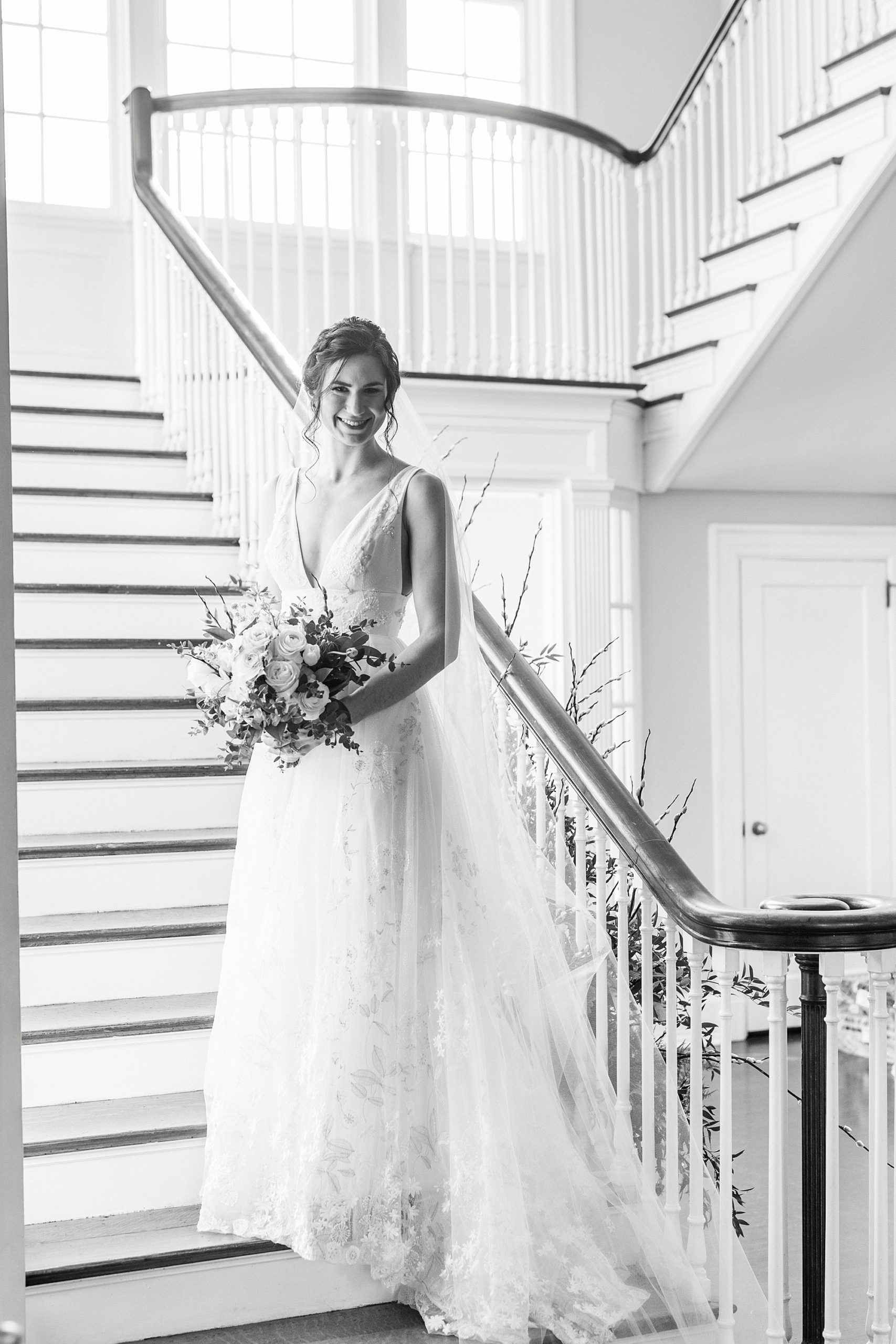 bride stands on staircase holding bouquet in front of her