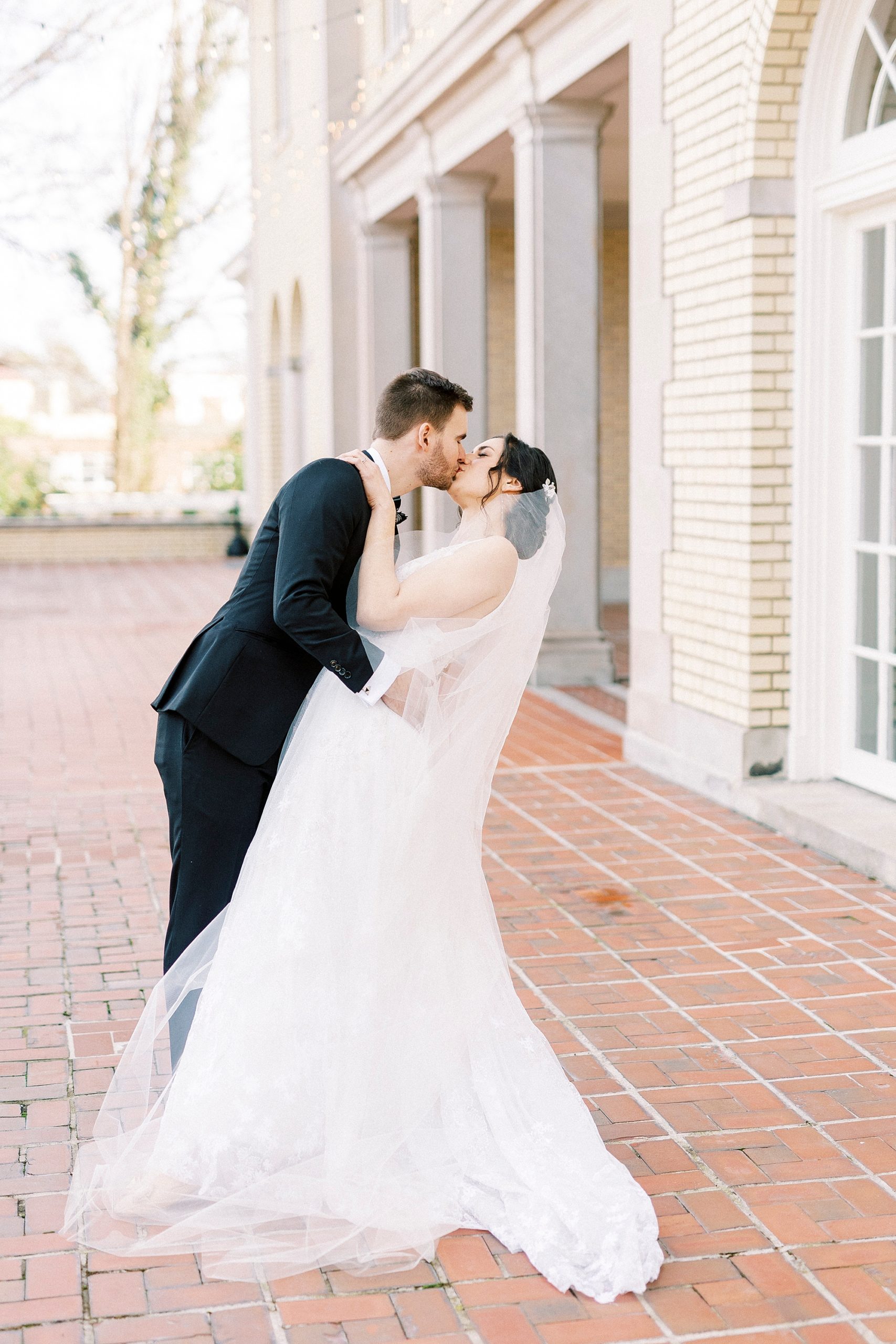 groom dips bride kissing her on brick patio at Separk Mansion