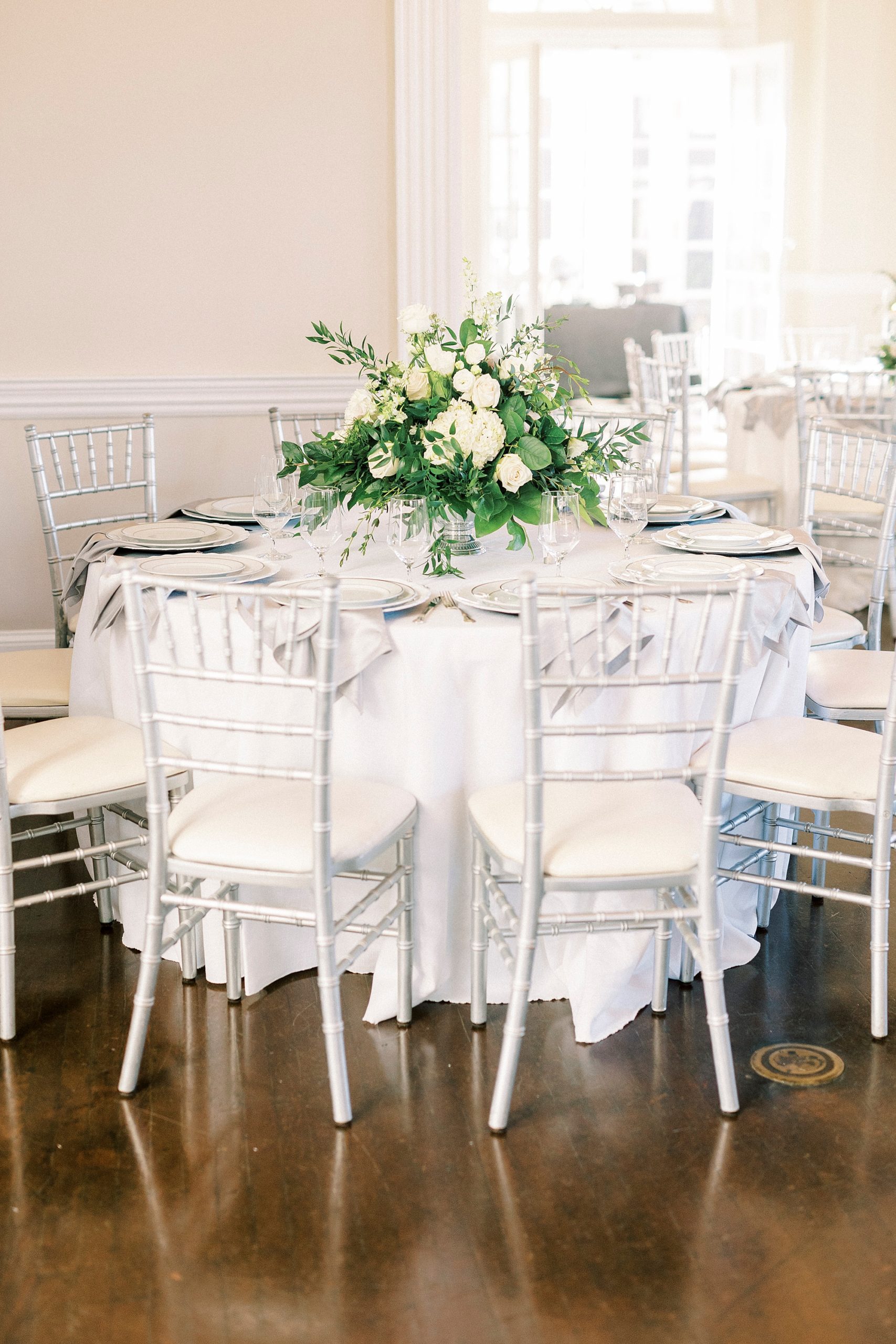 table with silver chivari chairs and white rose centerpieces for Grand Tasting Event at Separk Mansion in winter 2023 