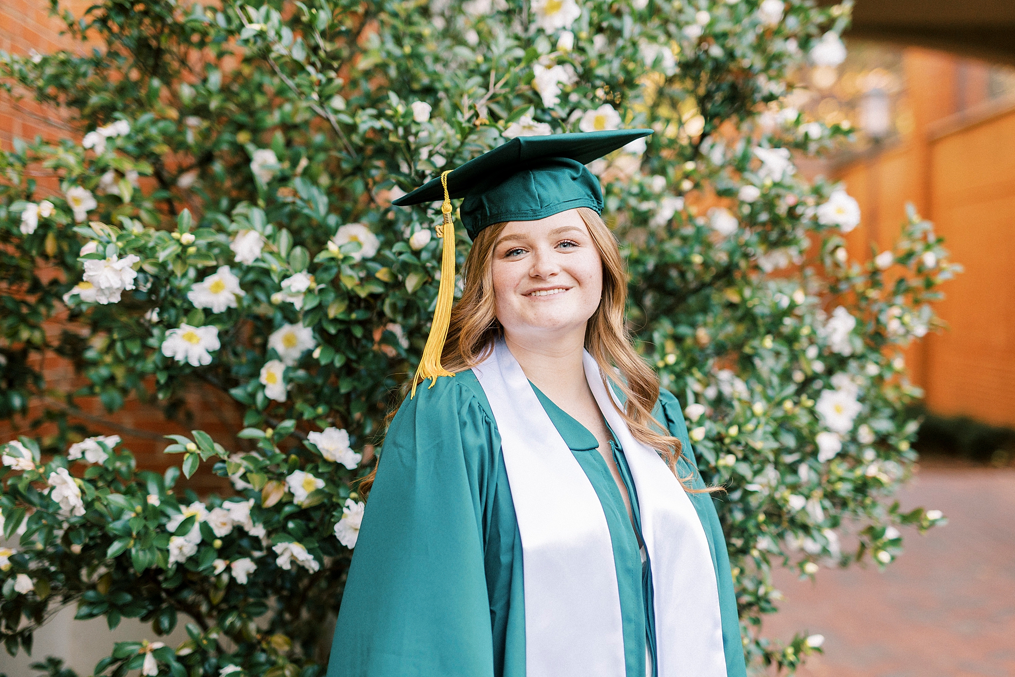 woman poses in front of white flowers during UNC Charlotte senior portraits