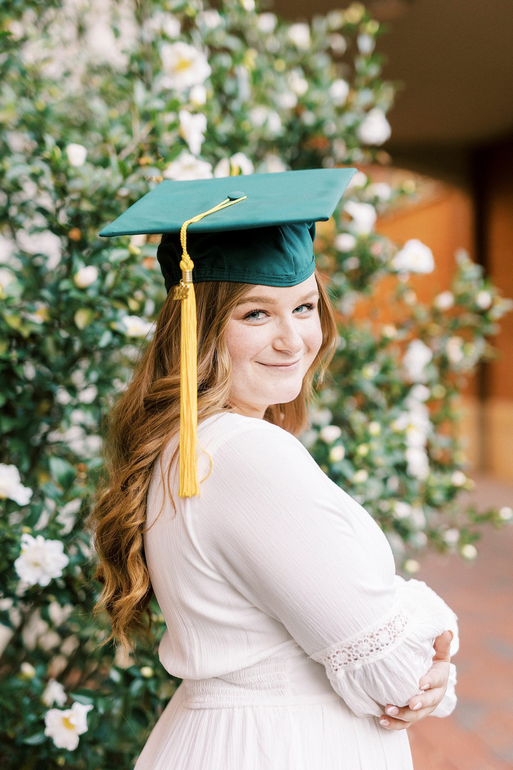 graduate looks over shoulder in white dress 