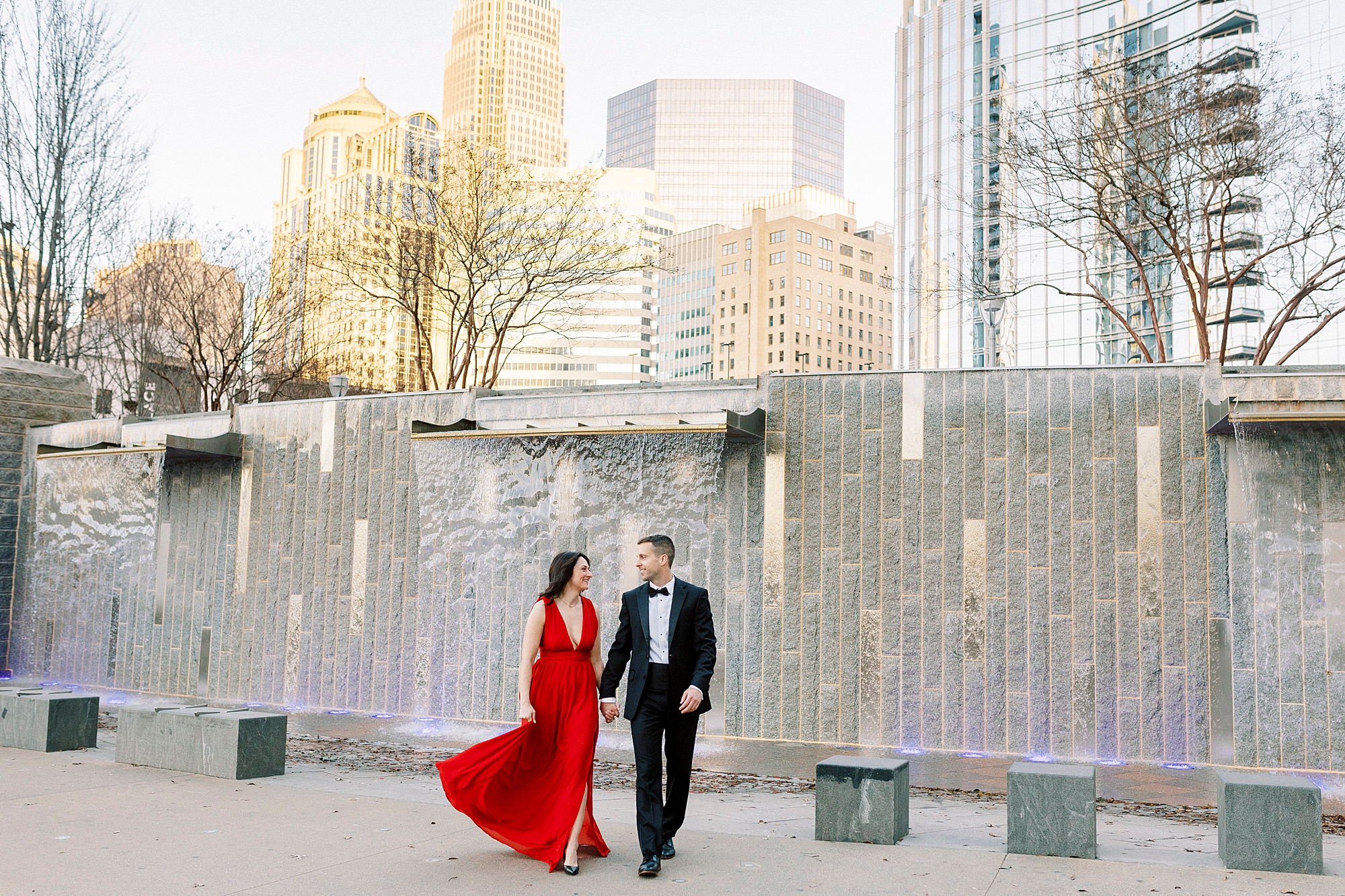 bride and groom hold ands walking by fountain in Romare Bearden Park