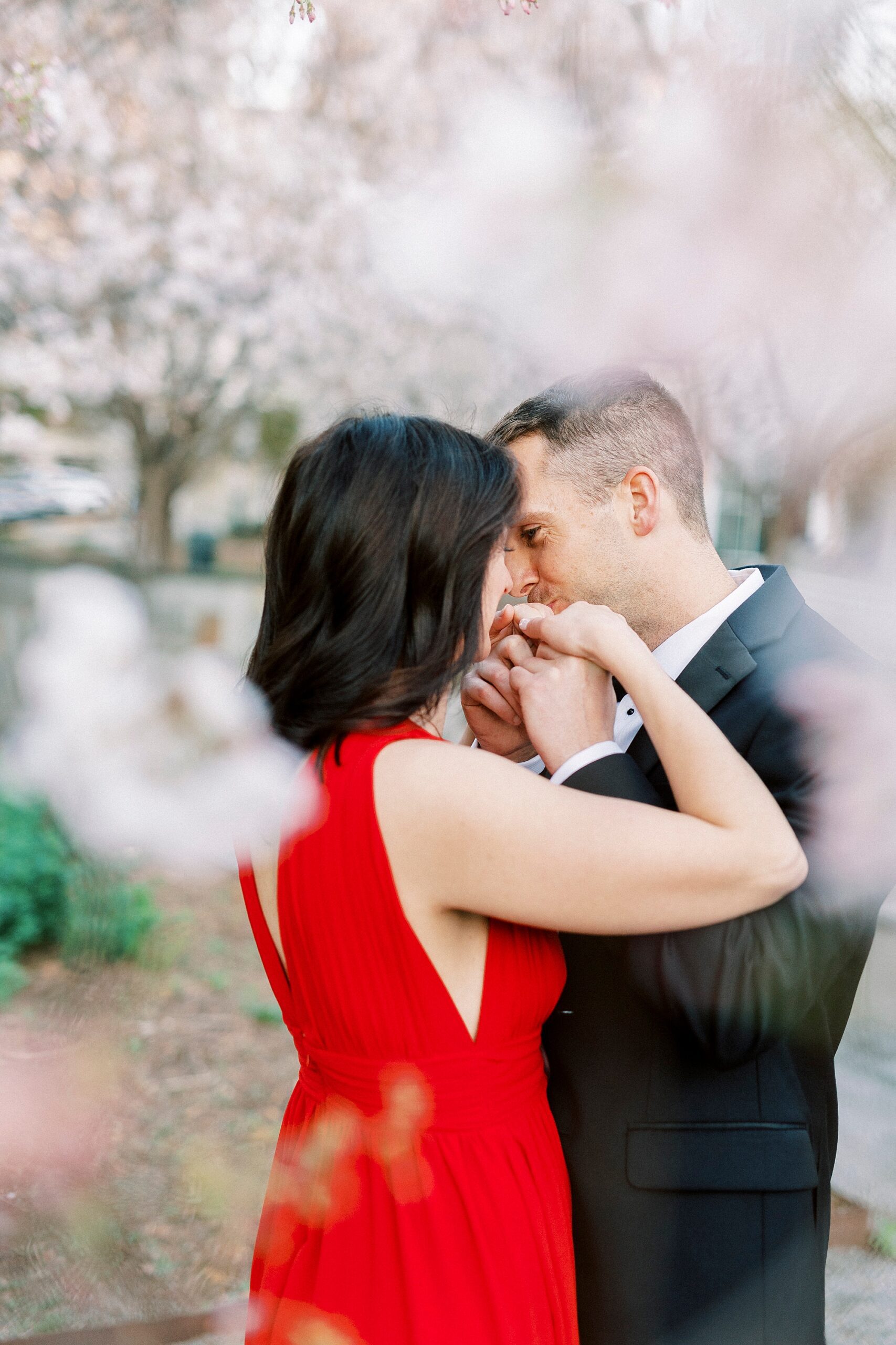 man kisses woman's hand during engagement session in Romare Bearden Park