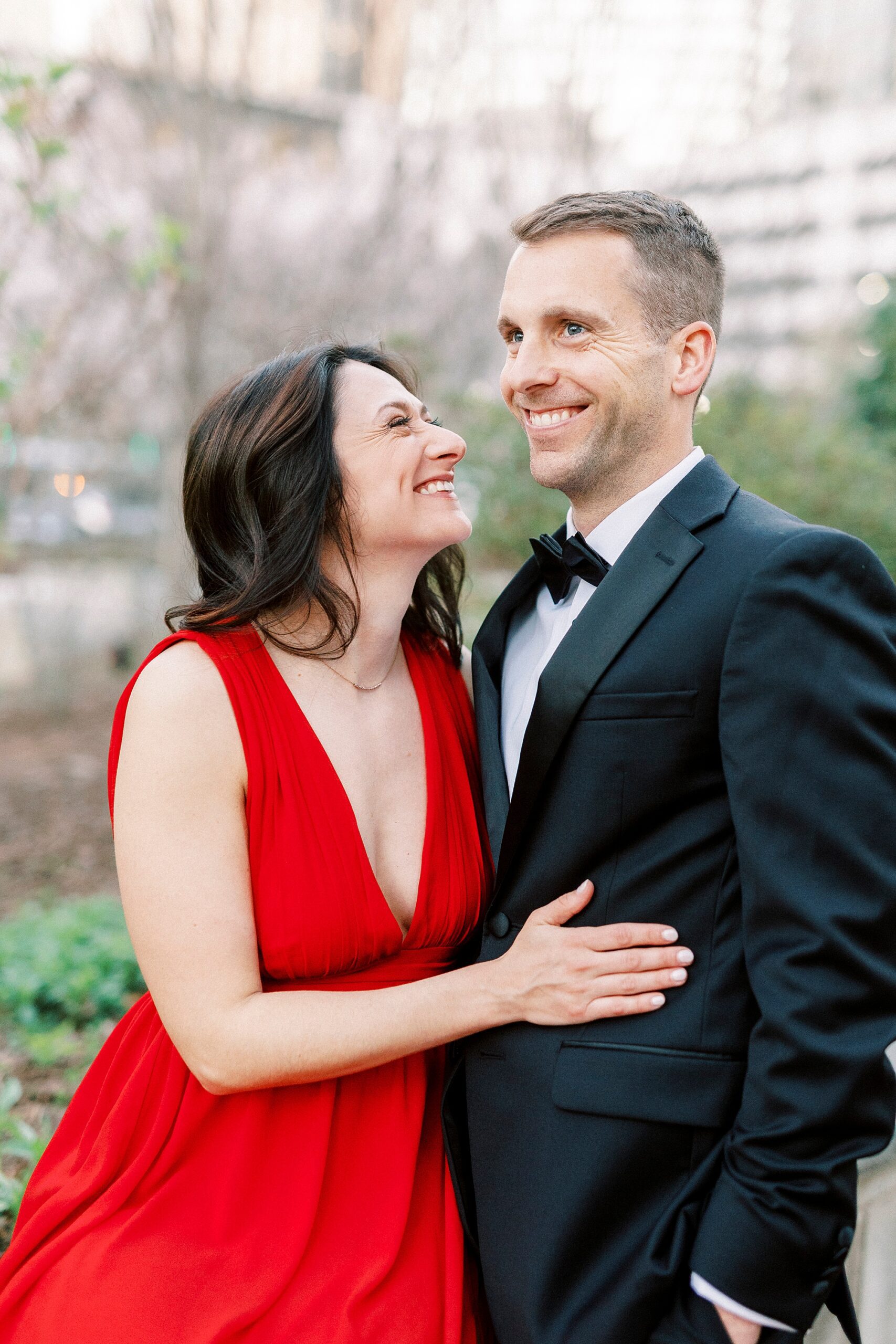 woman in red dress smiles up at groom in suit 