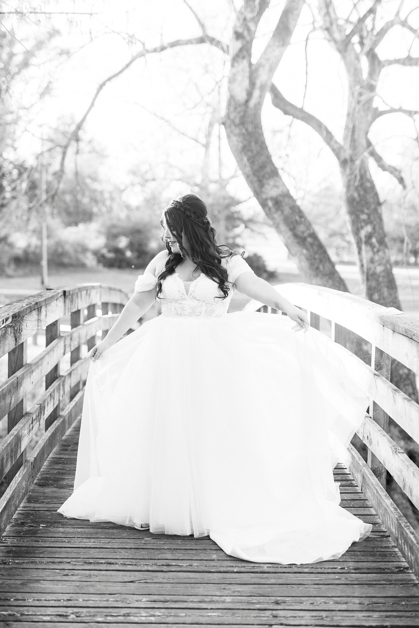 bride twirls wedding dress standing on wooden bridge in Sloan Park