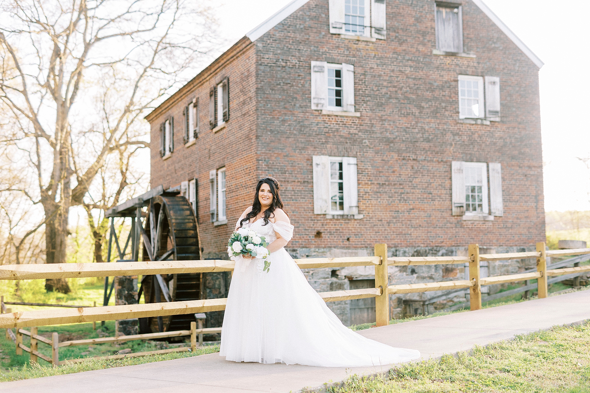 bride in off-the-shoulder gown walks by brick building in Sloan Park