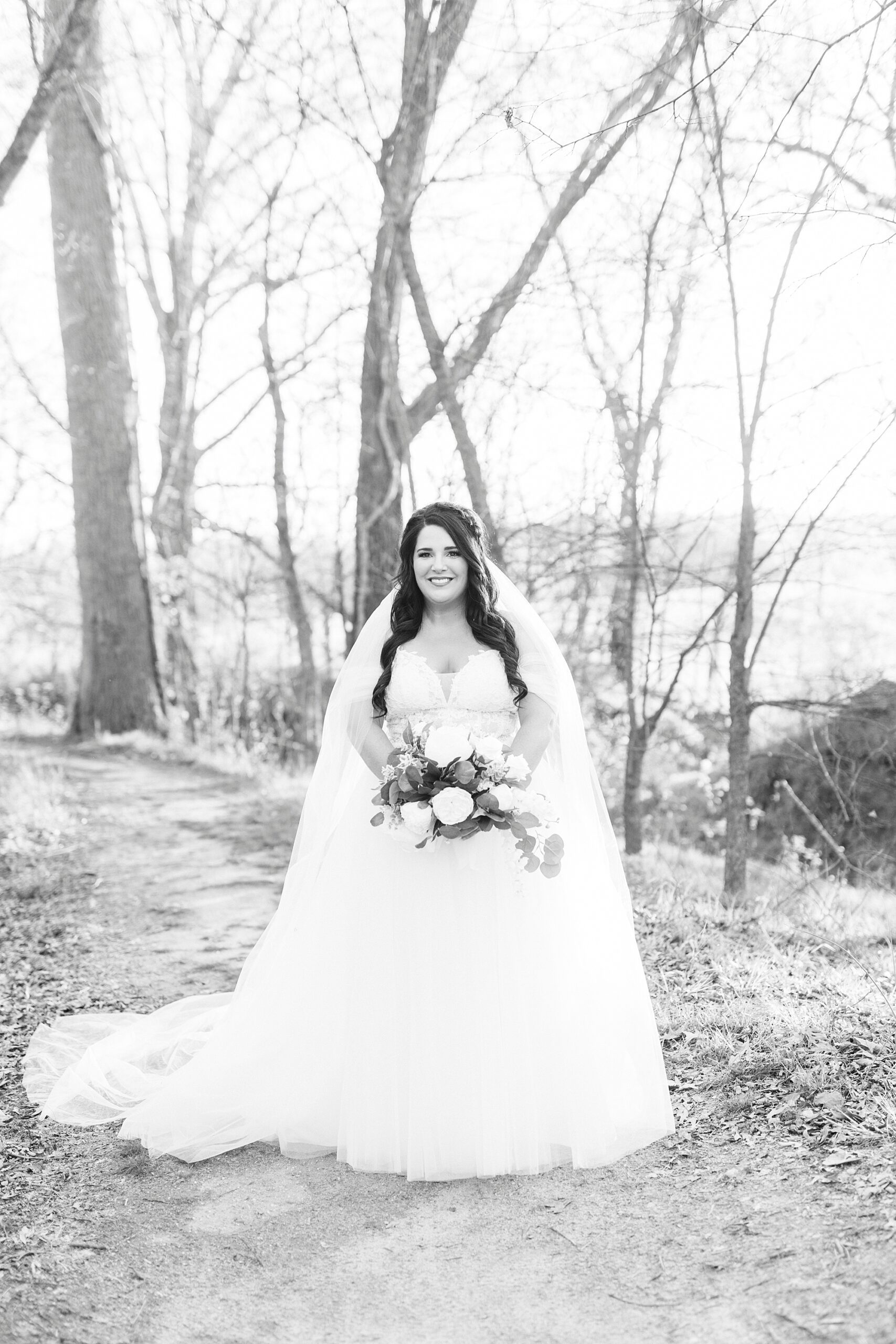 bride with veil around shoulders stands in Sloan Park