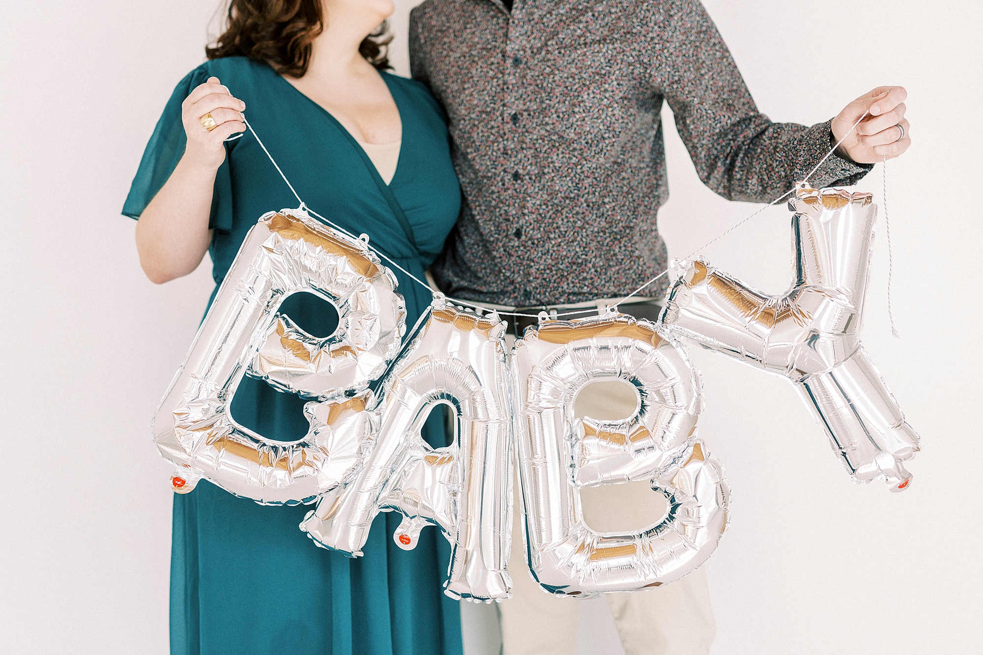 expecting parents hold silver baby sign