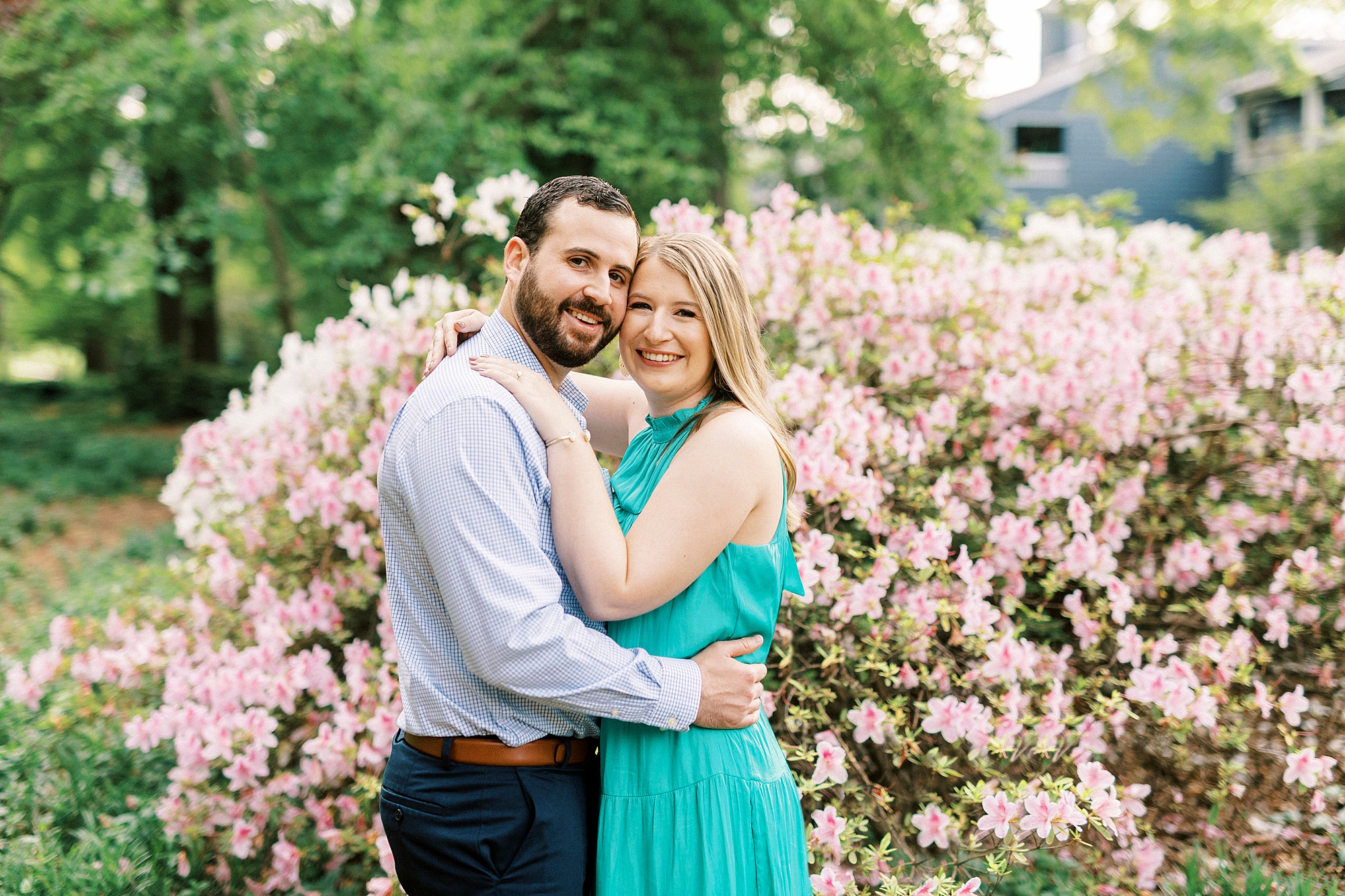 engaged couple hugs by pink bush during Fourth Ward Park engagement session 
