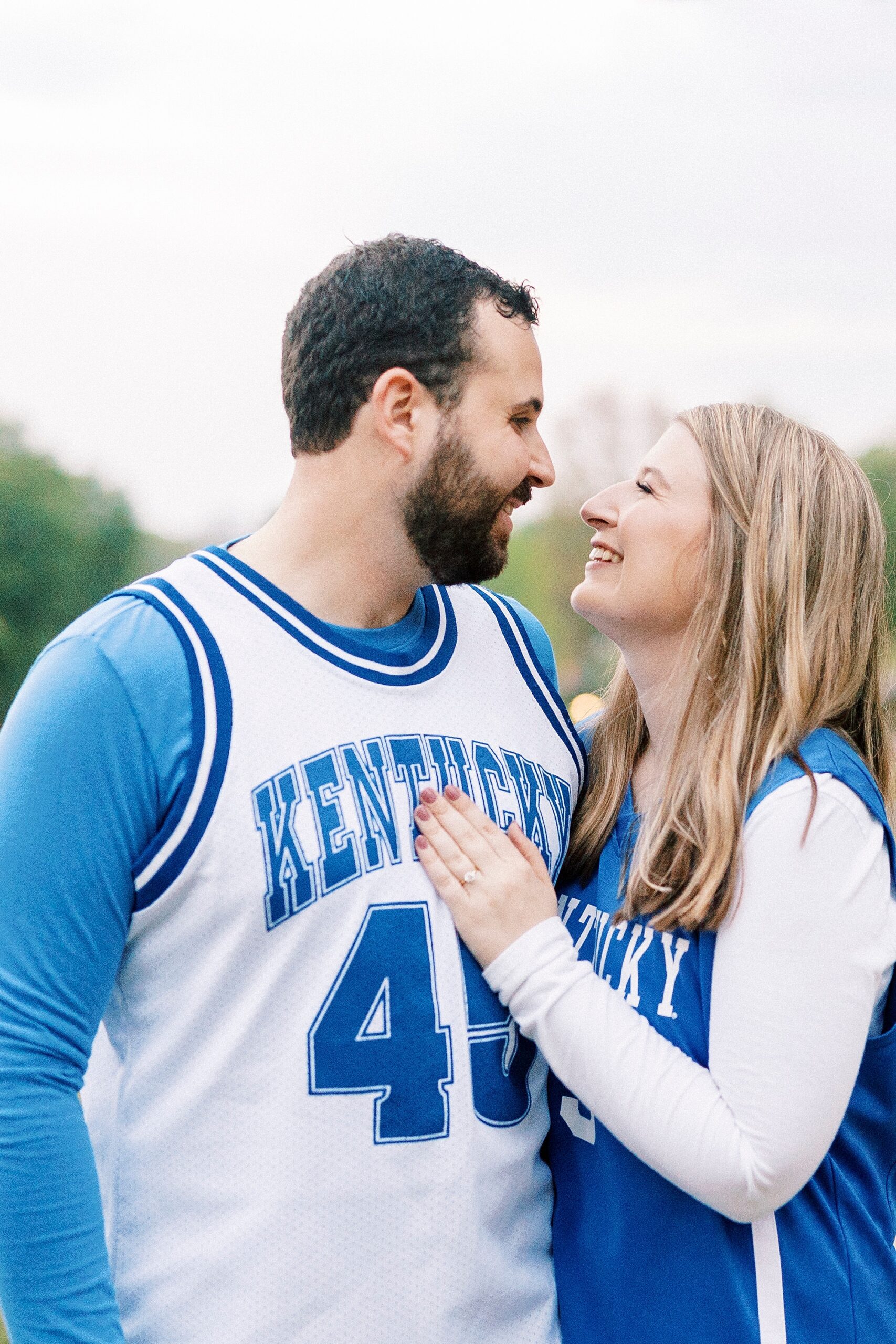 engaged couple hugs in matching Kentucky jerseys at Freedom Park