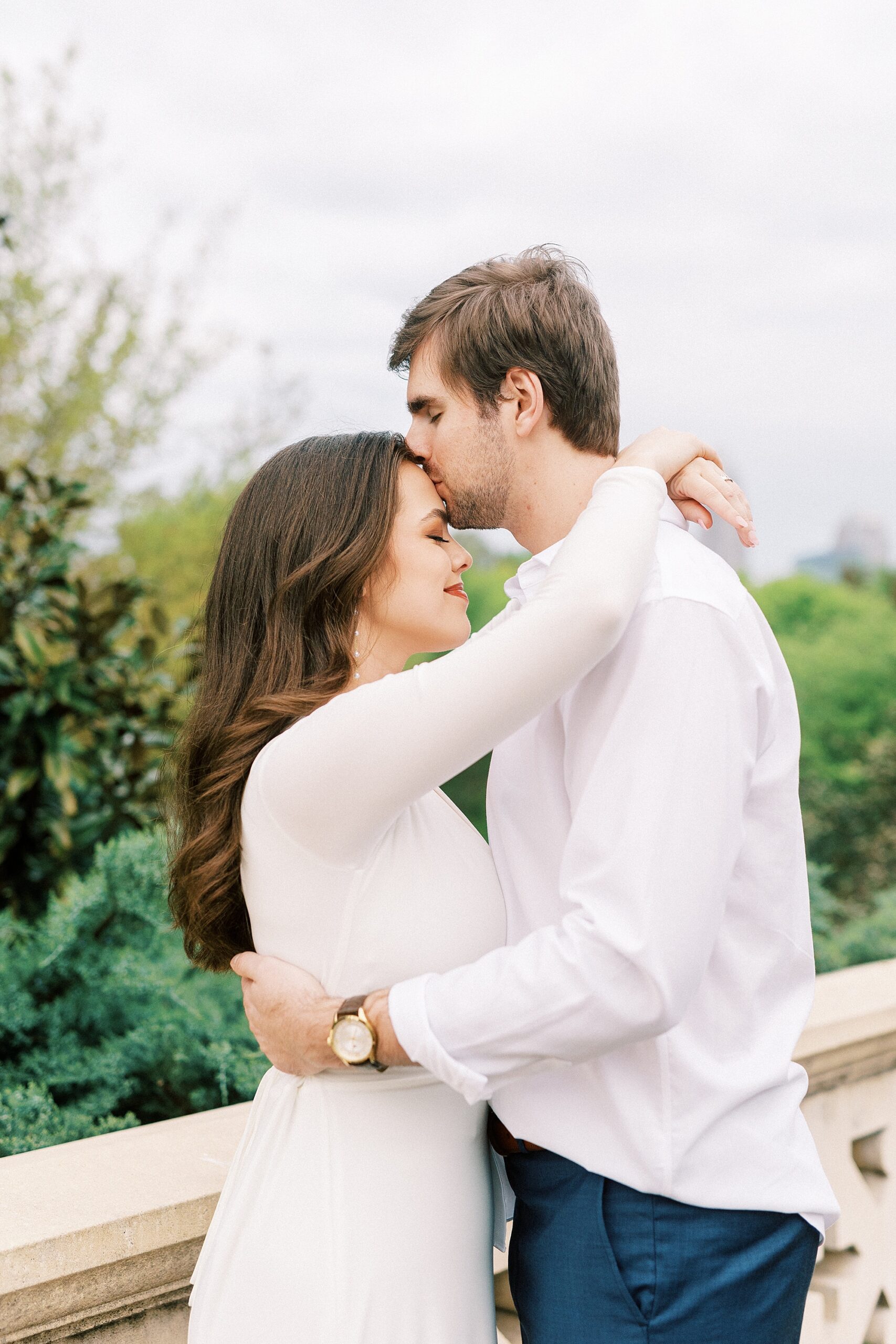 groom in white shirt hugs woman in white dress during Midtown Park engagement session 
