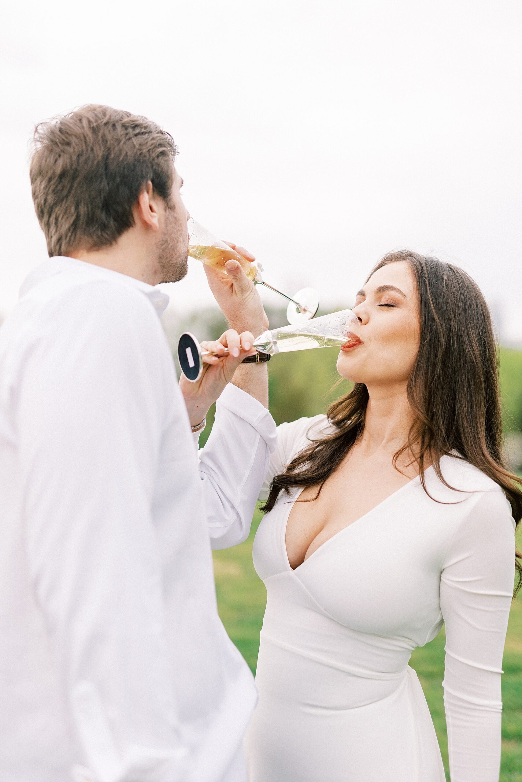 man and woman link arms to drink champagne during Midtown Park engagement session 