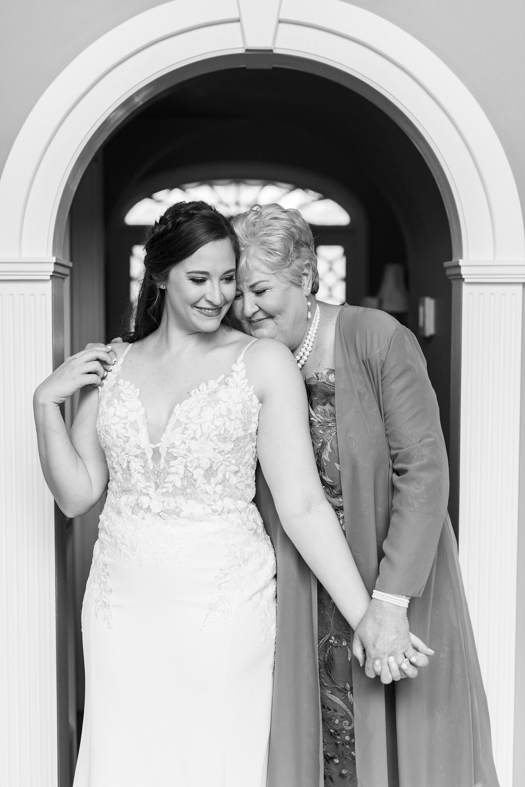 bride holds mom's hand smiling in archway at The Saratoga Springs
