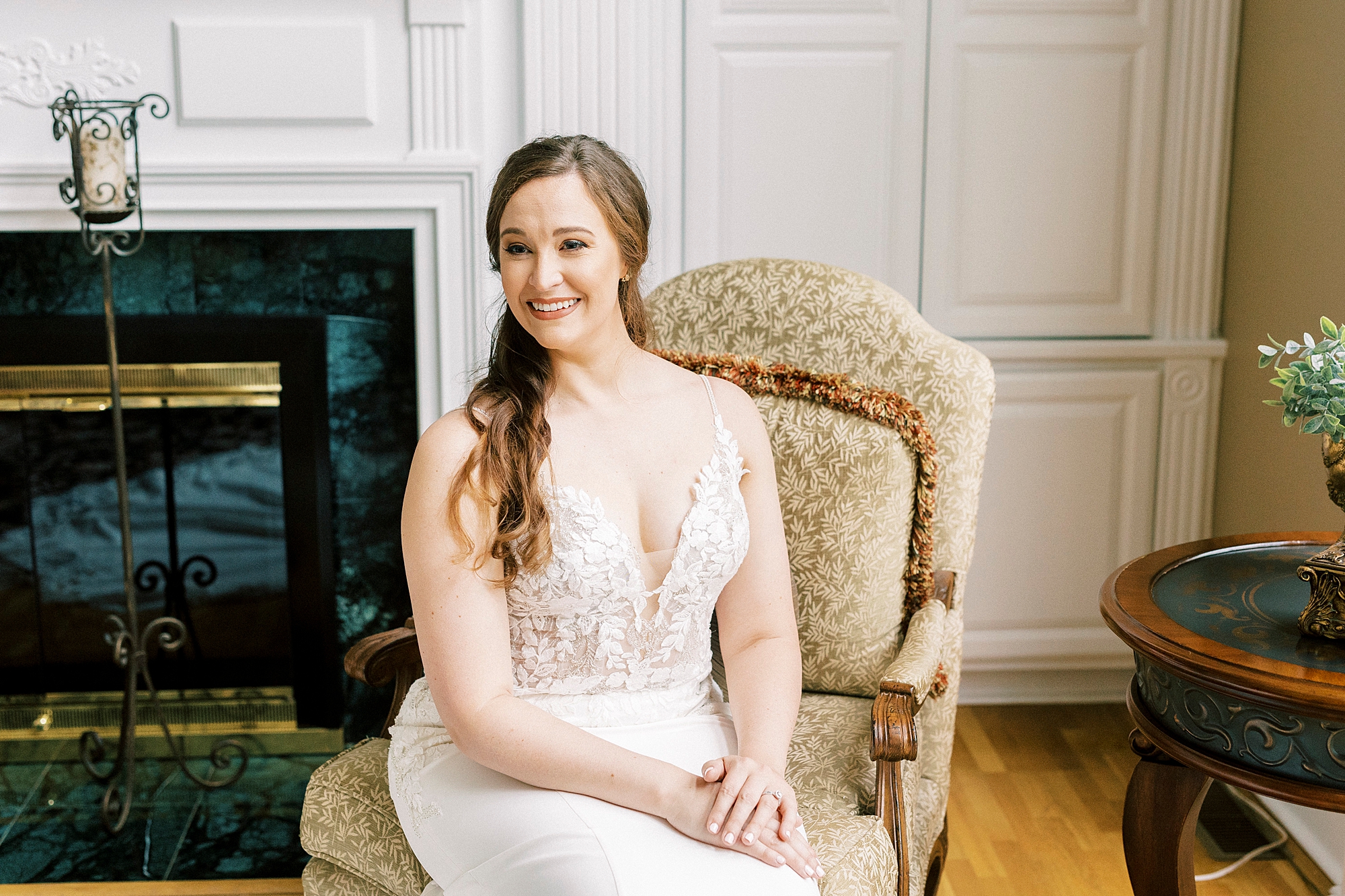 bride sits in gold chair in front of fireplace at The Saratoga Springs
