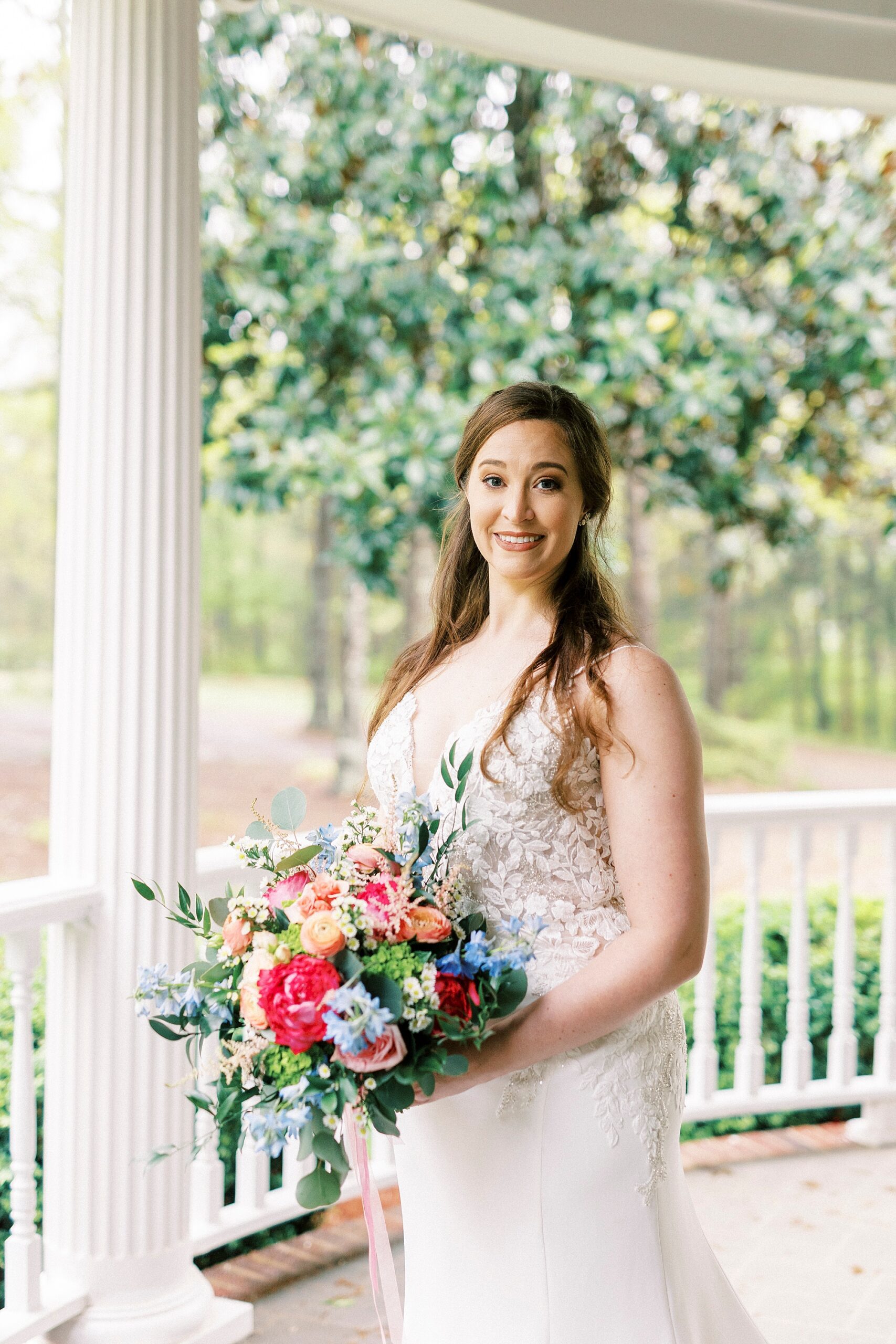 bride stands holding bouquet of pink and orange flowers 