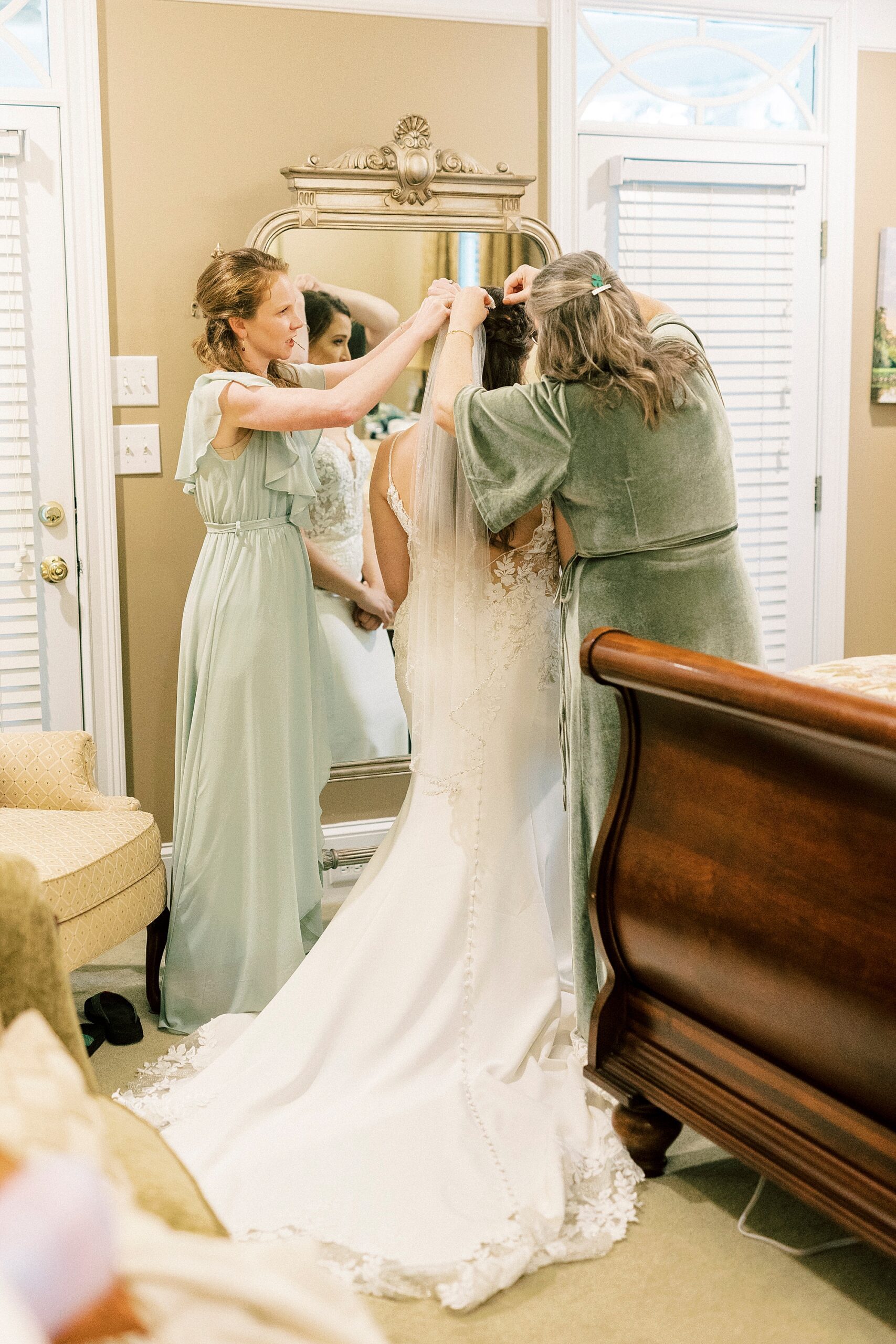 mother and bridesmaids help pin veil on bride's head 
