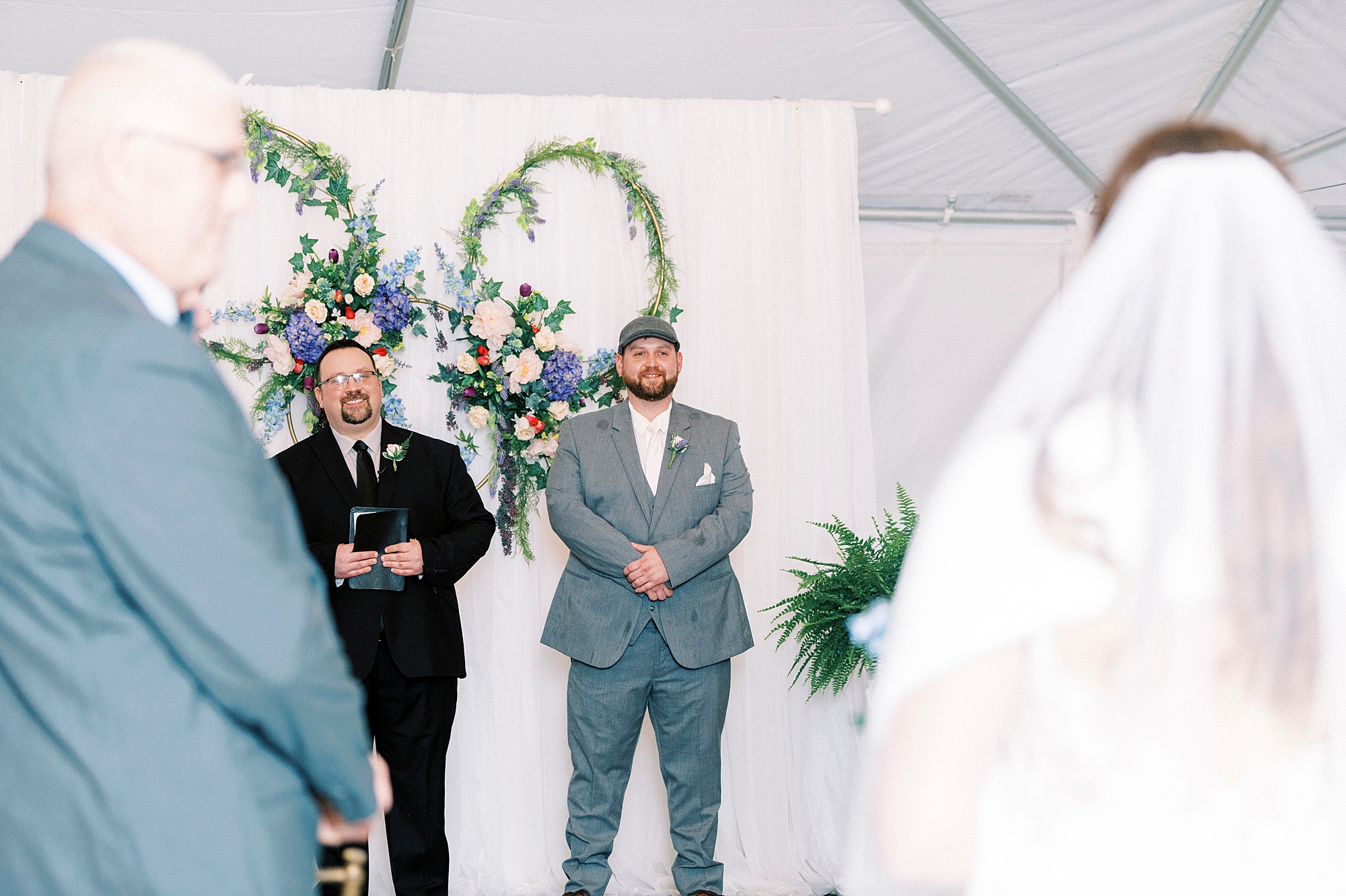 groom in grey suit watches bride walk down aisle for wedding ceremony at The Saratoga Springs