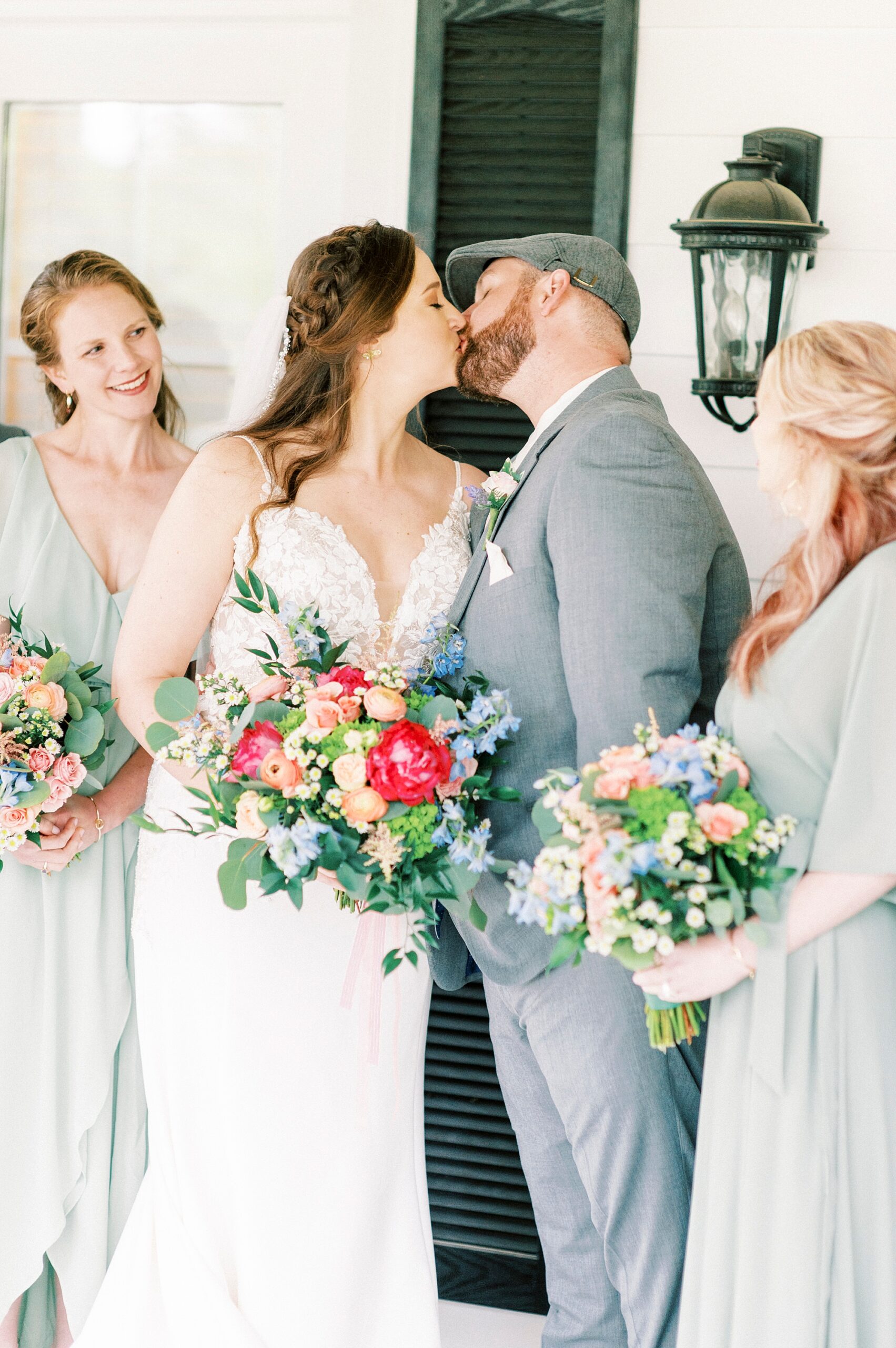 bride and groom kiss with bridesmaids on the porch at The Saratoga Springs
