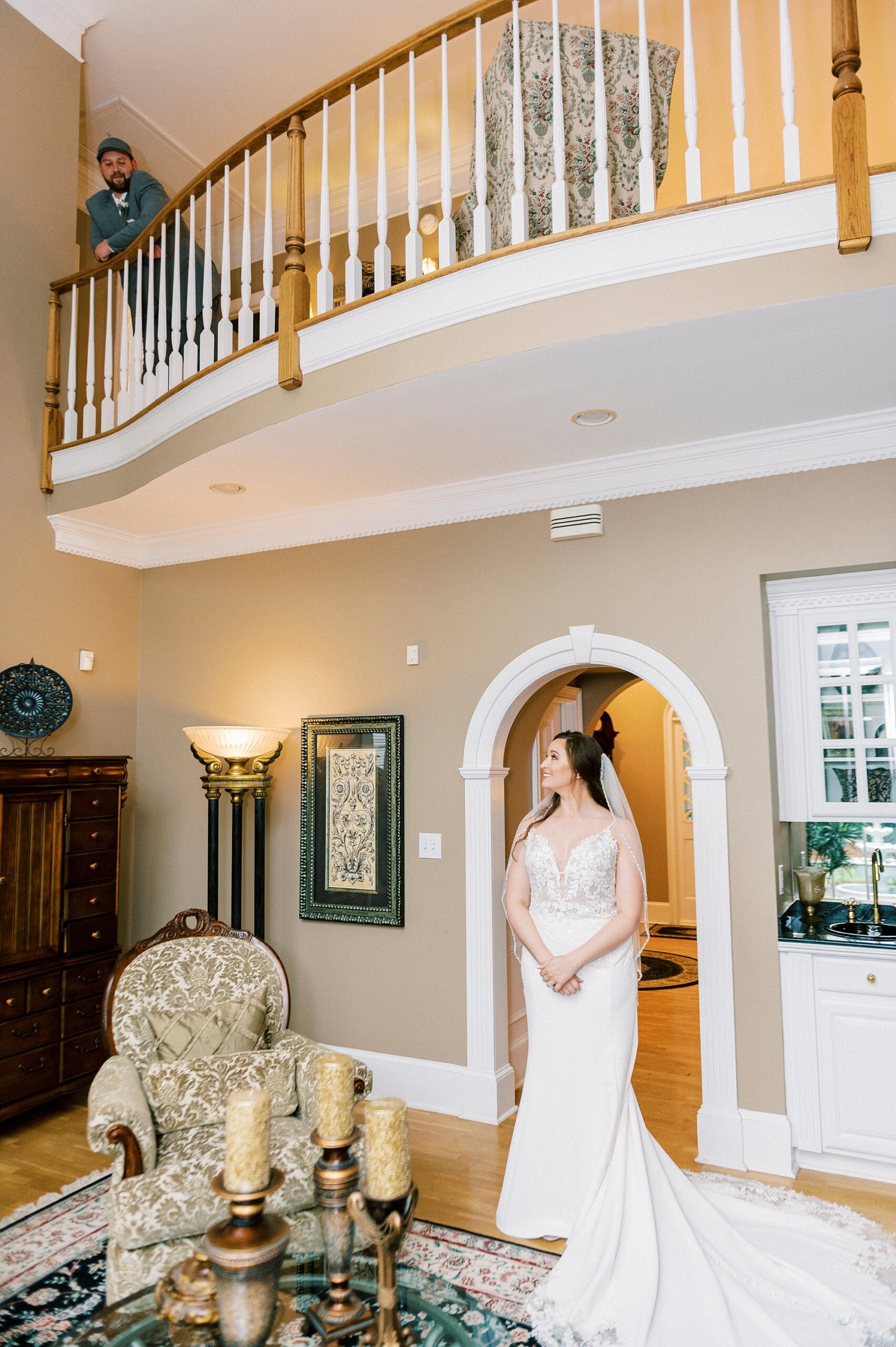 bride stands in sitting room at the The Saratoga Springs while groom stands on balcony above her 