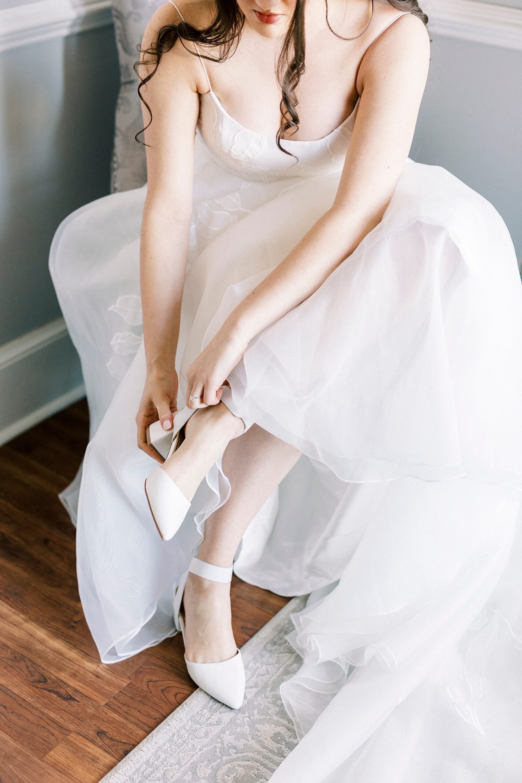 bride adjusts white shoe sitting in wedding gown 