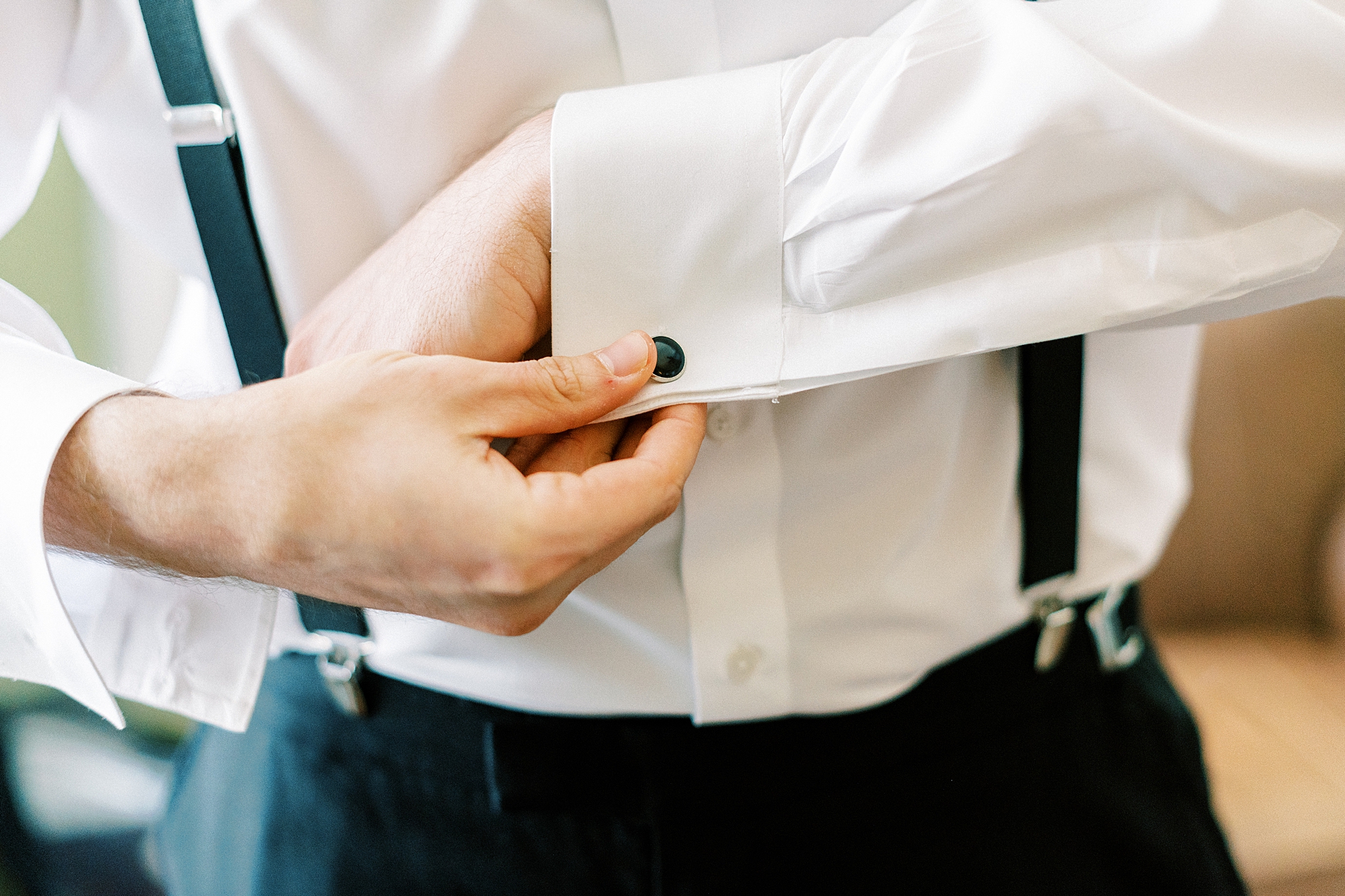 groom adjusts black button on white shirt 
