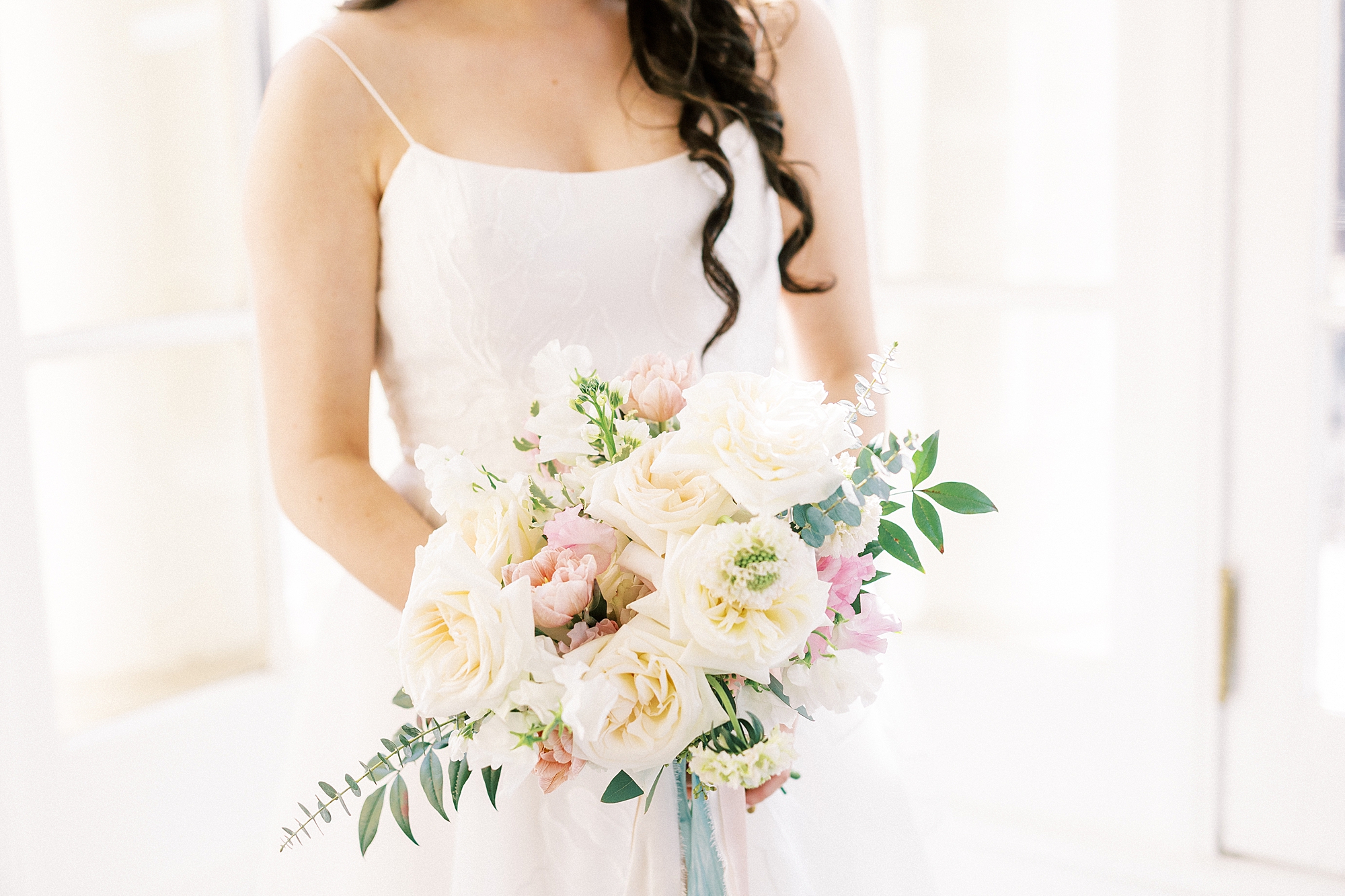 bride holds bouquet of pastel flowers in sunroom at Separk Mansion