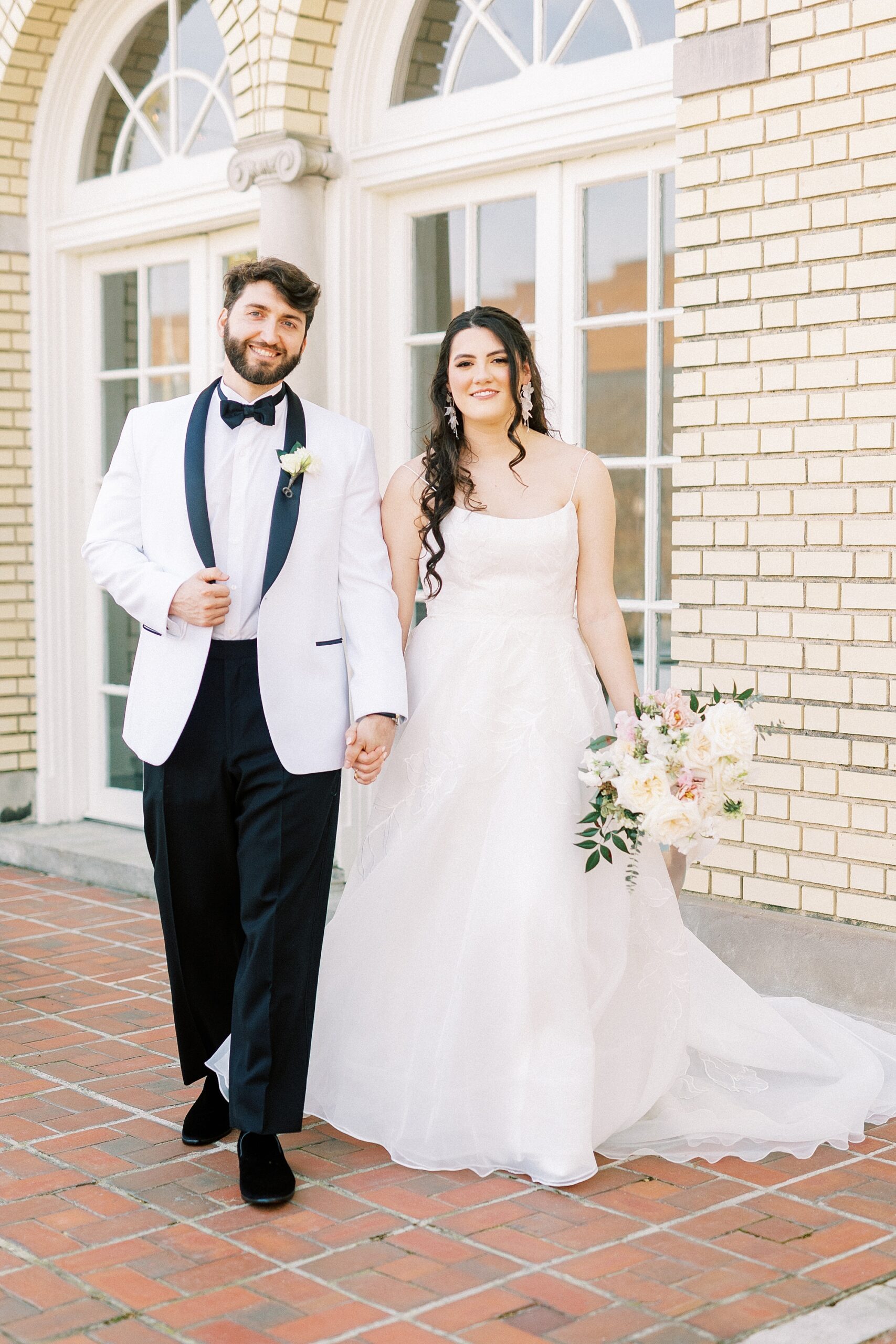 newlyweds hold hands walking on brick patio at Separk Mansion