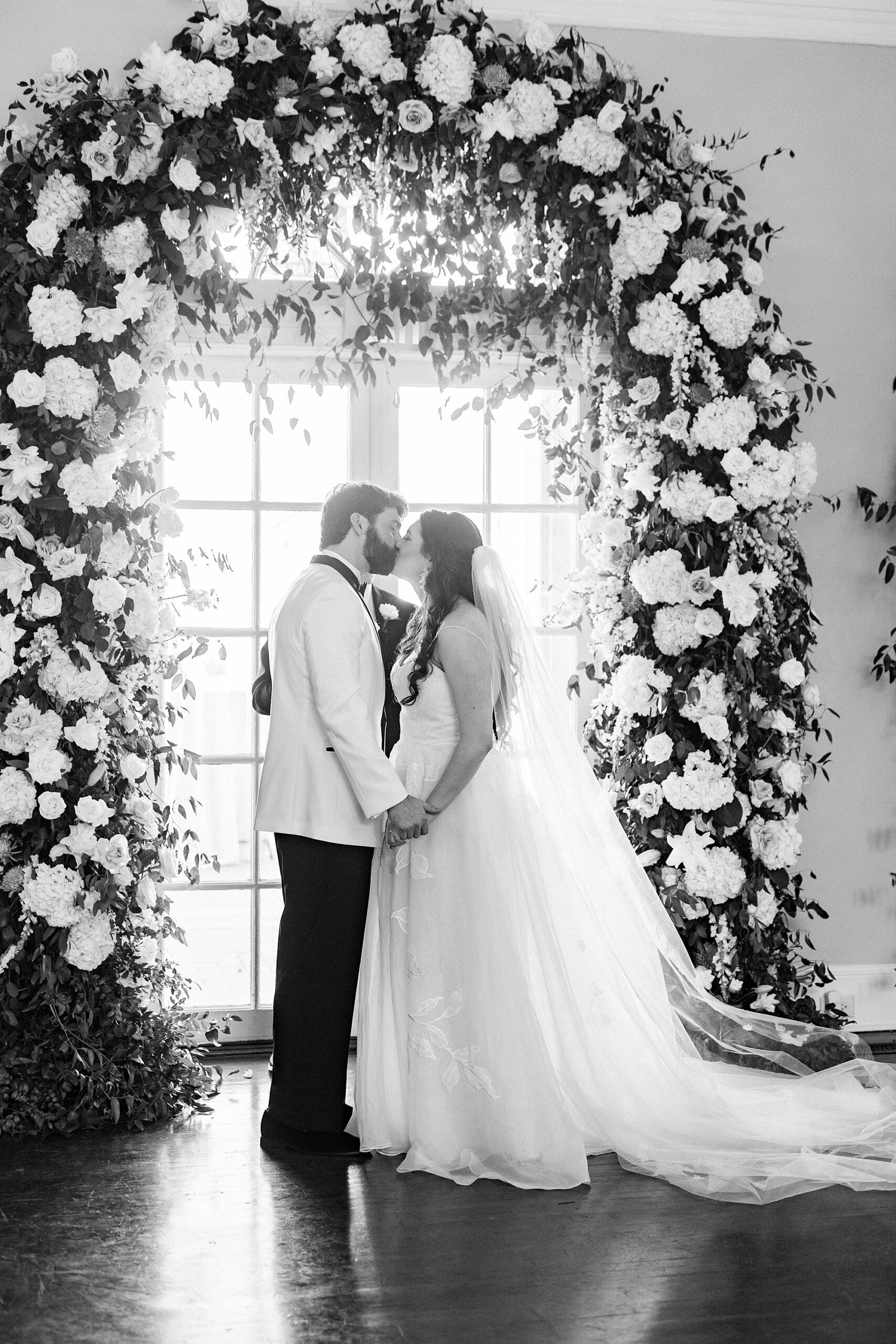 bride and groom kiss in front of window with floral arch at Separk Mansion