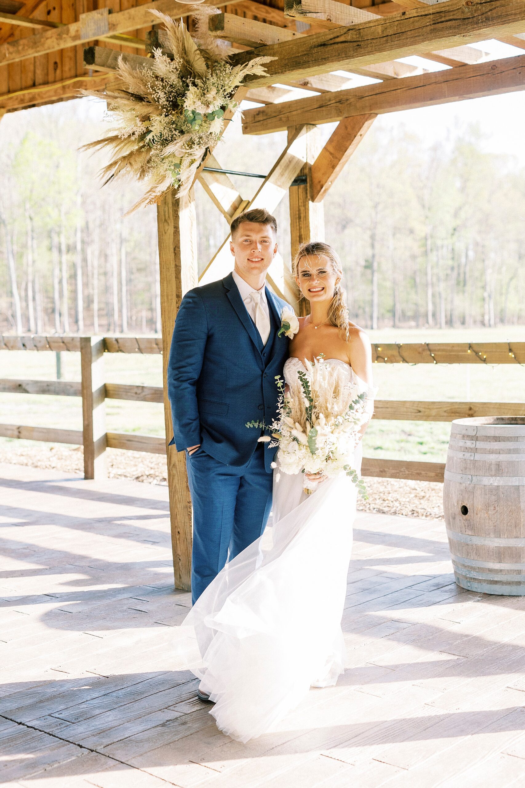 newlyweds pose near wooden fence at the Farmstead