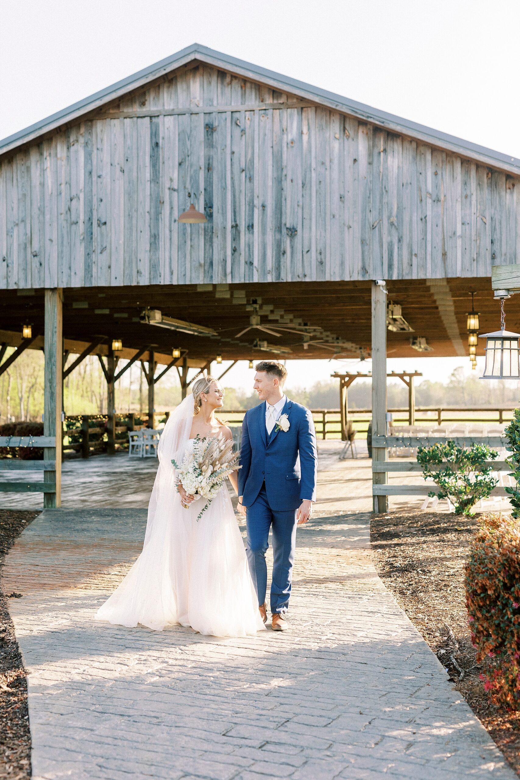 bride and groom hold hands walking outside barn at the Farmstead
