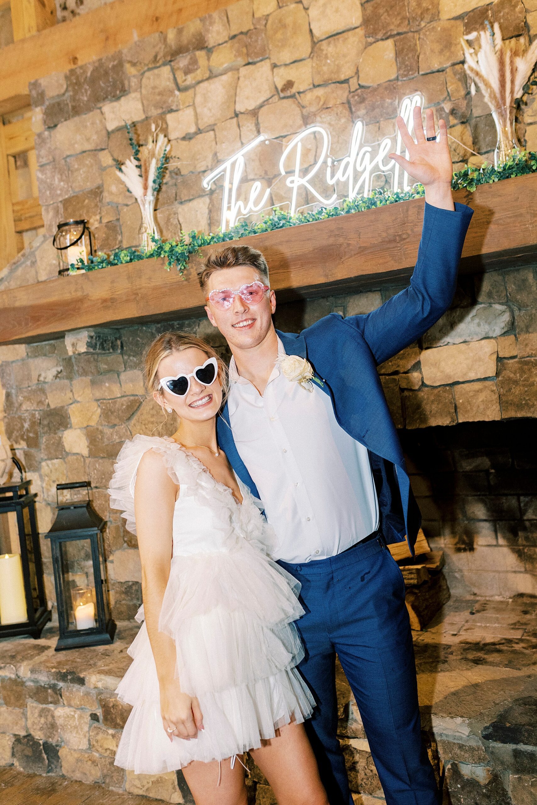 newlyweds hug by fireplace with silly heart glasses