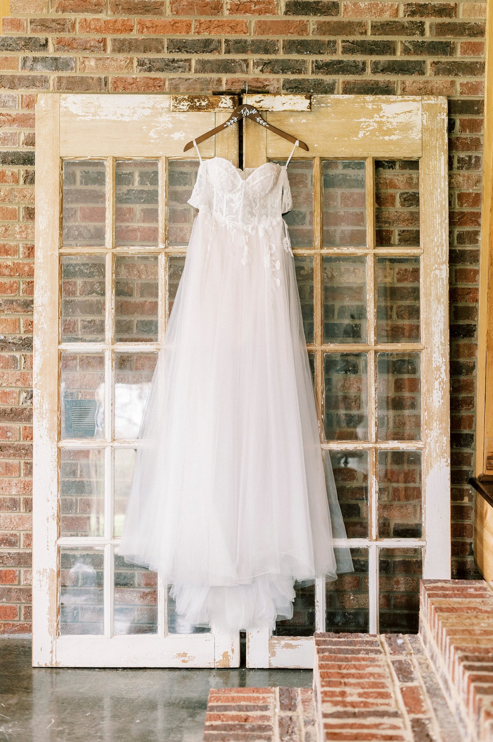 wedding dress hangs on glass door 