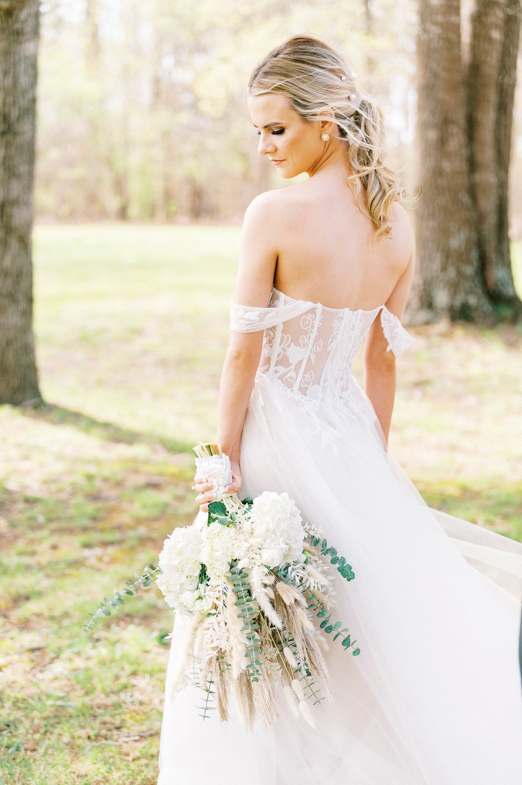 bride holds bouquet of white wildflowers and Rhodes grass 