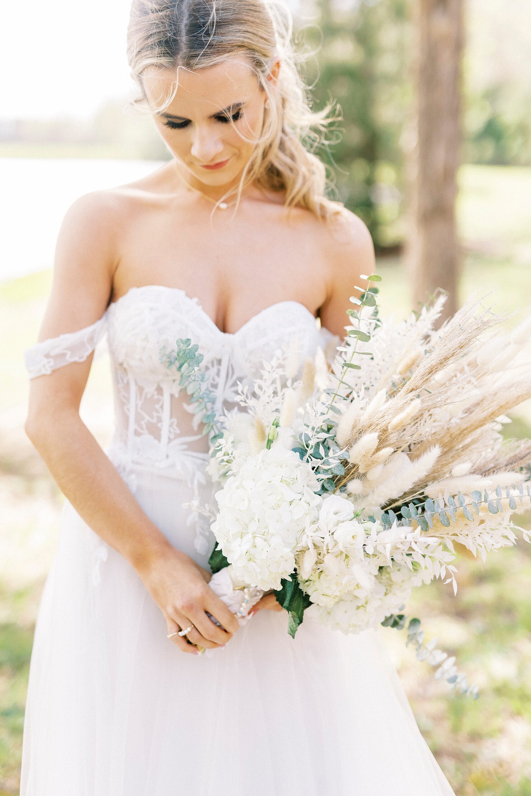 bride holds bouquet of white flowers and Rhodes grass in wedding dress with corset bodice 