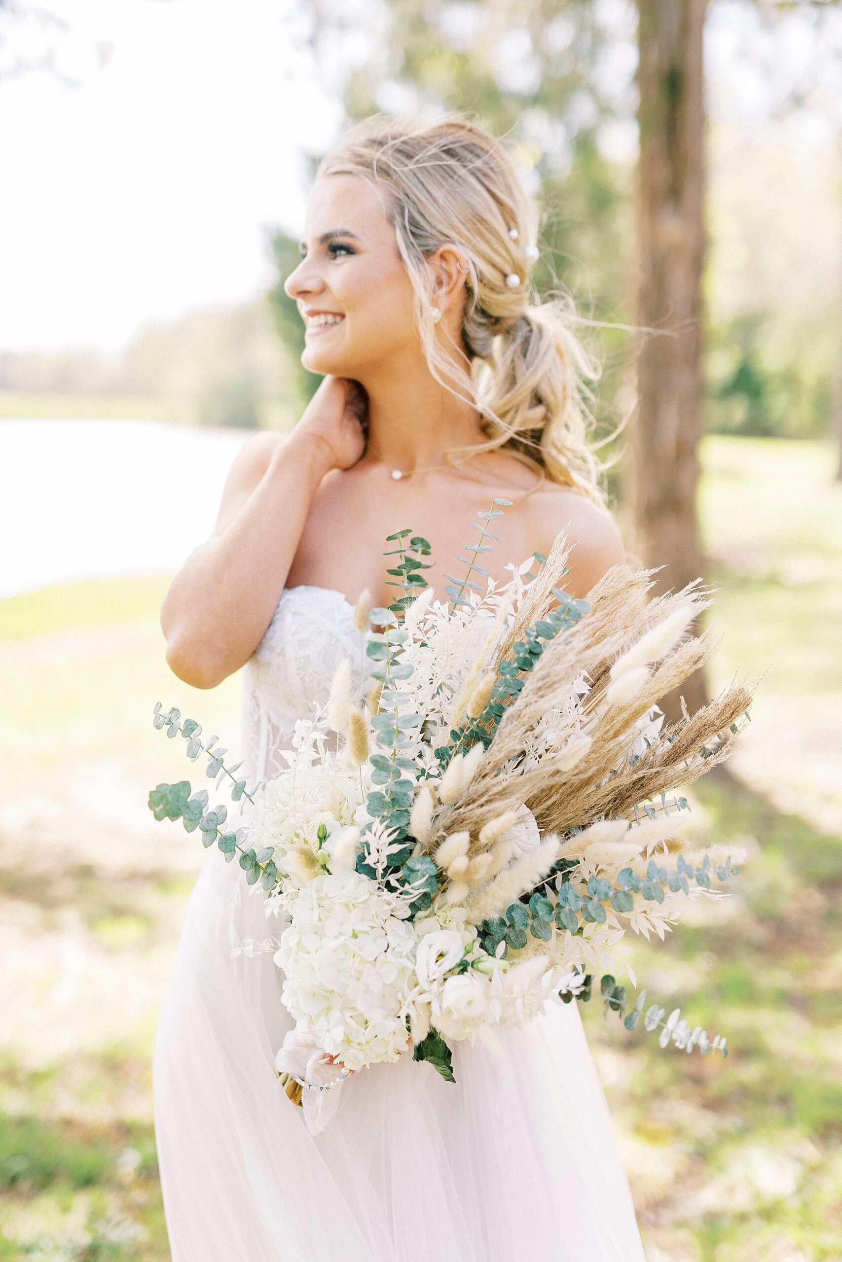 bride holds bouquet of white flowers, eucalyptus leaves and Rhodes grass 