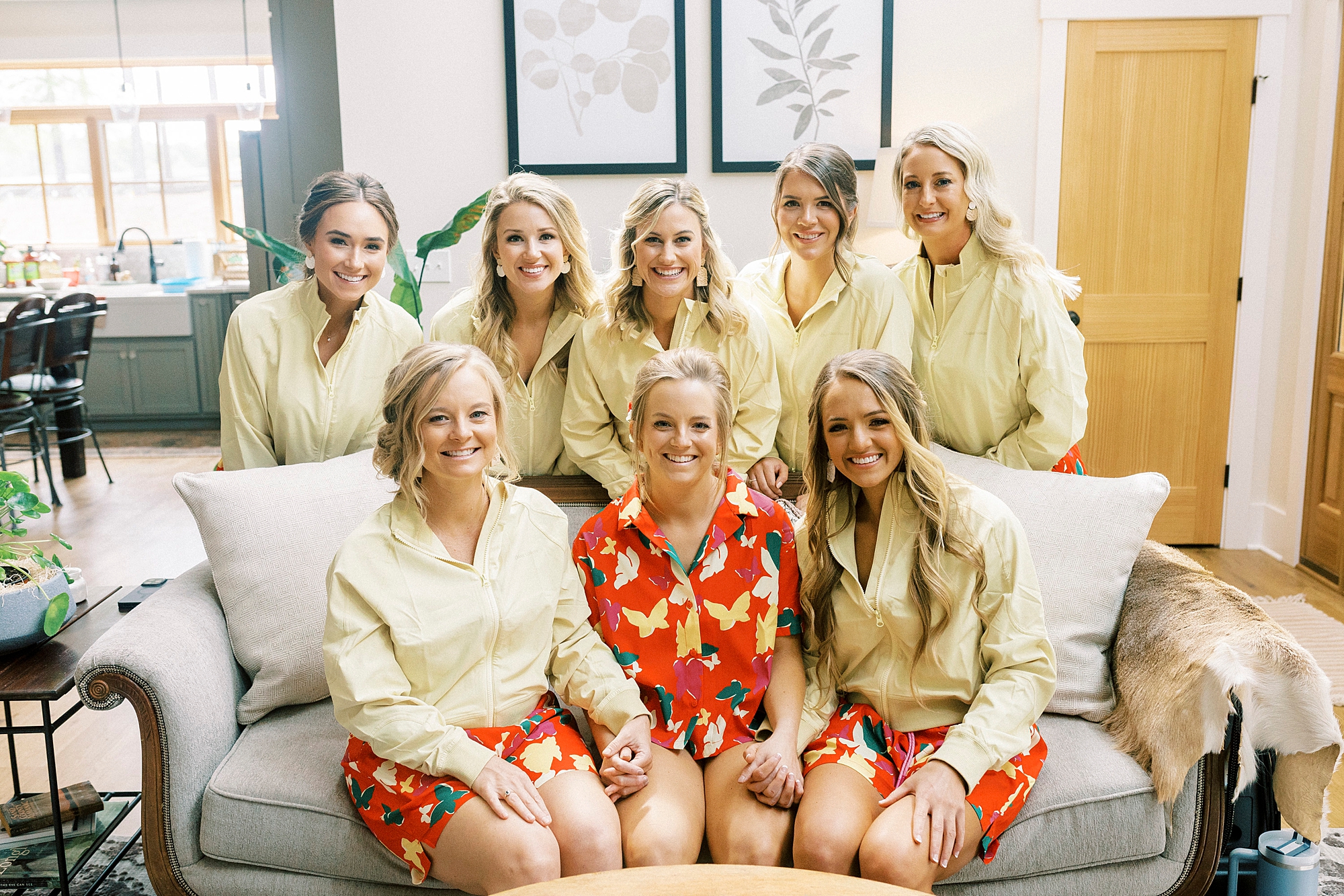 bride sits on couch with bridesmaids in floral pajamas 