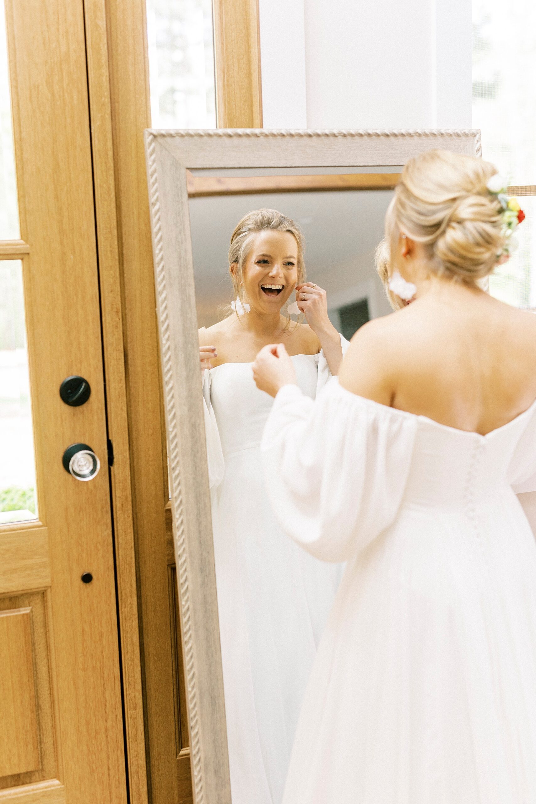 bride grins looking in the mirror in boho inspired wedding dress 