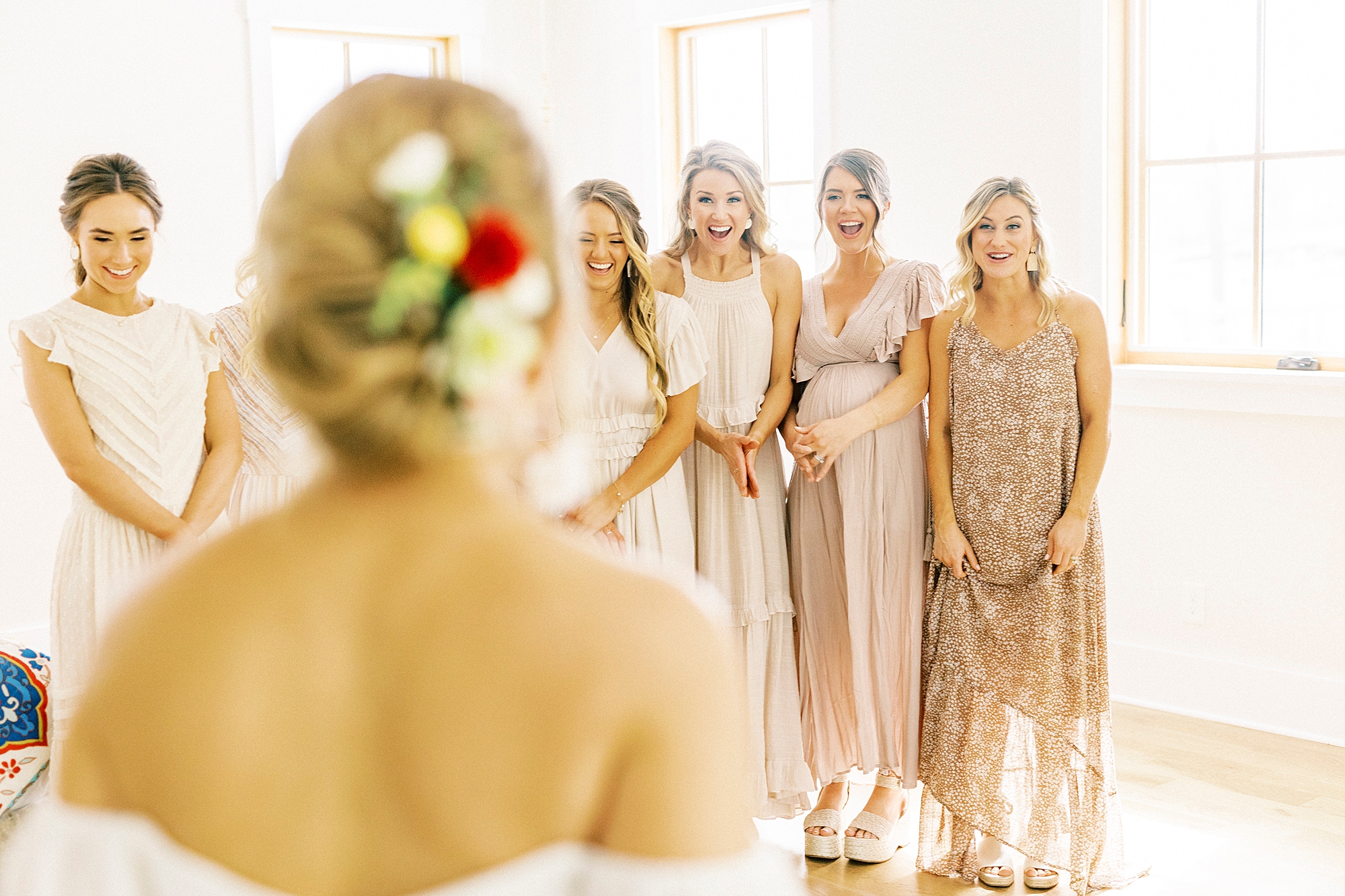 bride has first look with bridesmaids in mismatched pink dresses 