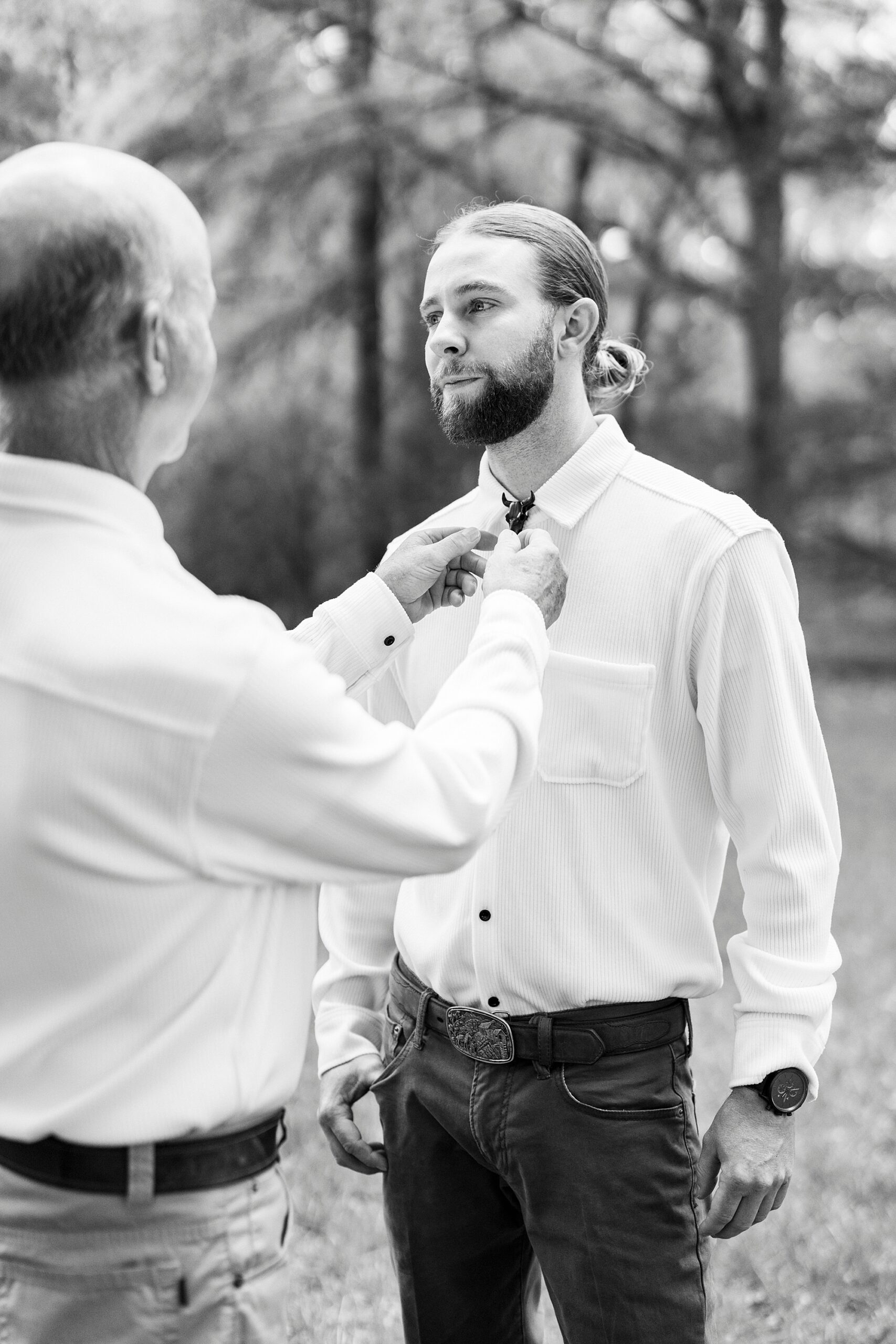 father helps groom with bolo tie
