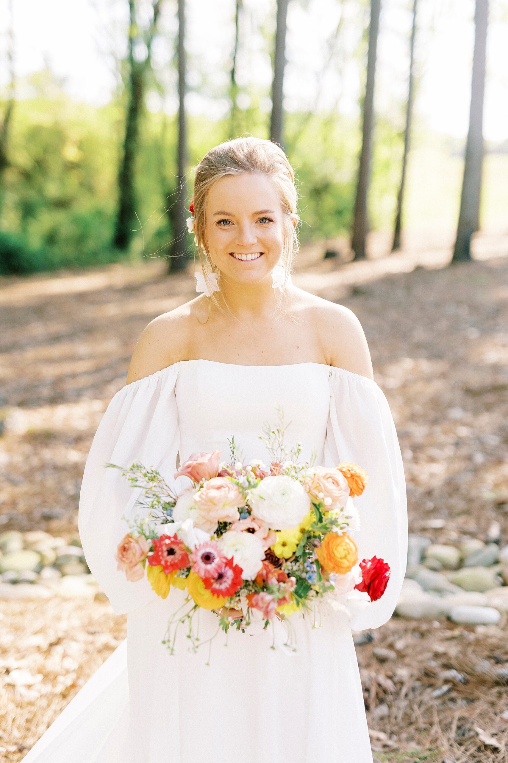 bride holds bouquet of yellow, orange, and red flowers in boho inspired wedding gown 