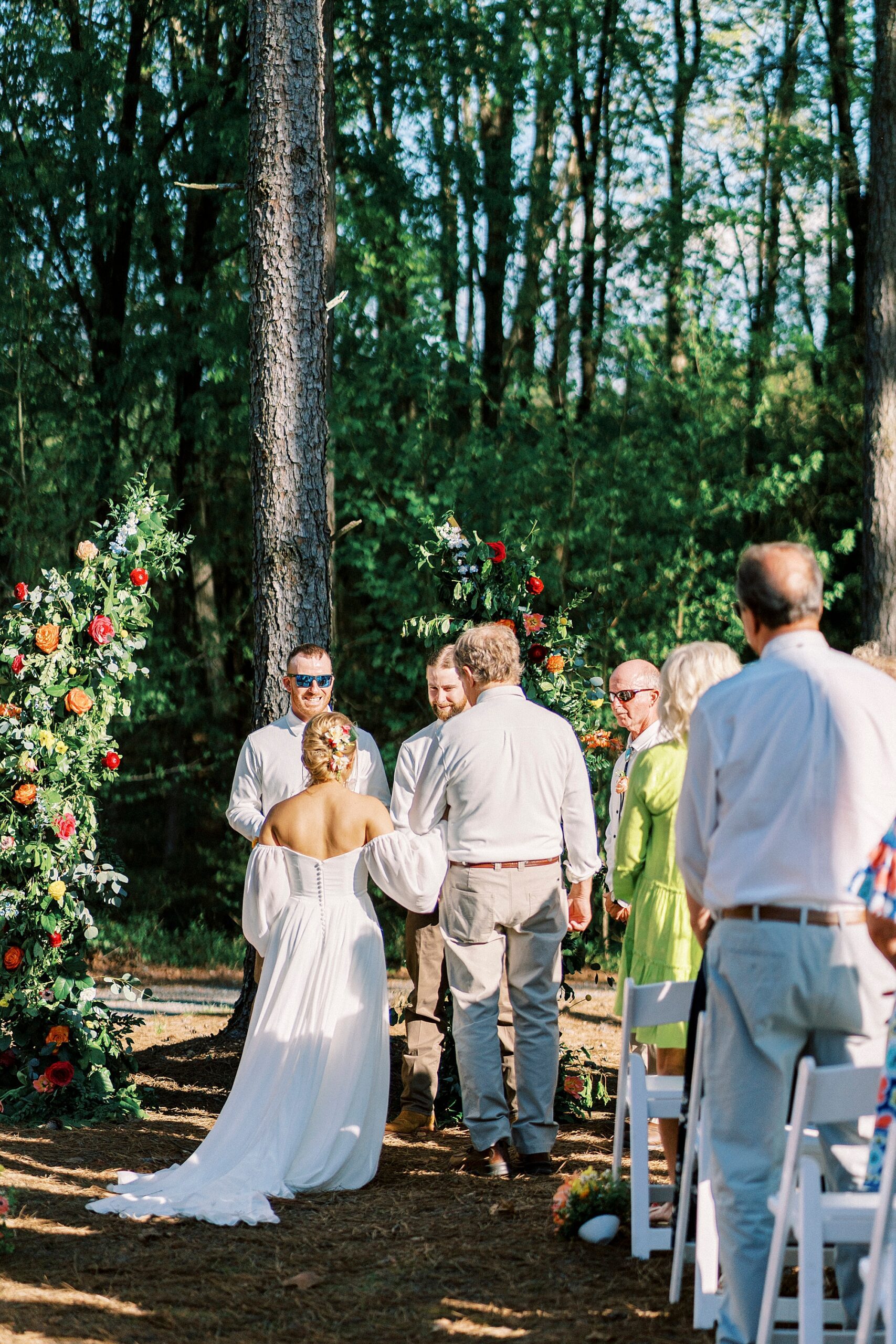 father stands with bride and groom during wedding ceremony on lawn of Richfield NC home