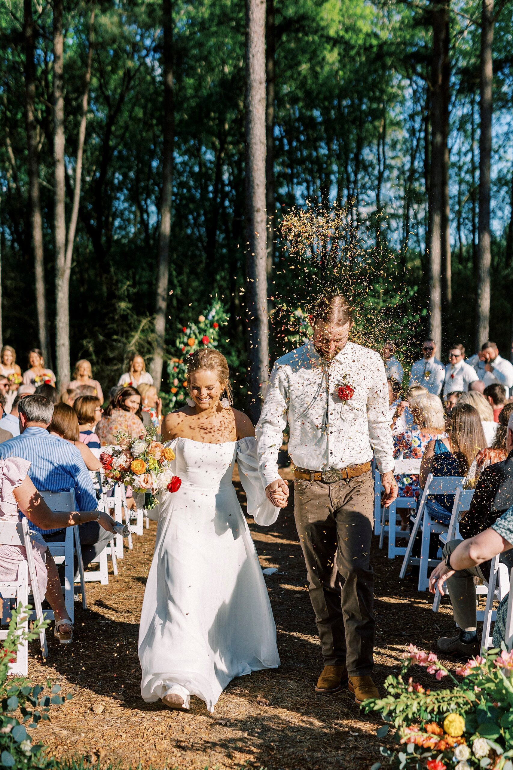 newlyweds hold hands walking up aisle after wedding ceremony on lawn of Richfield NC home
