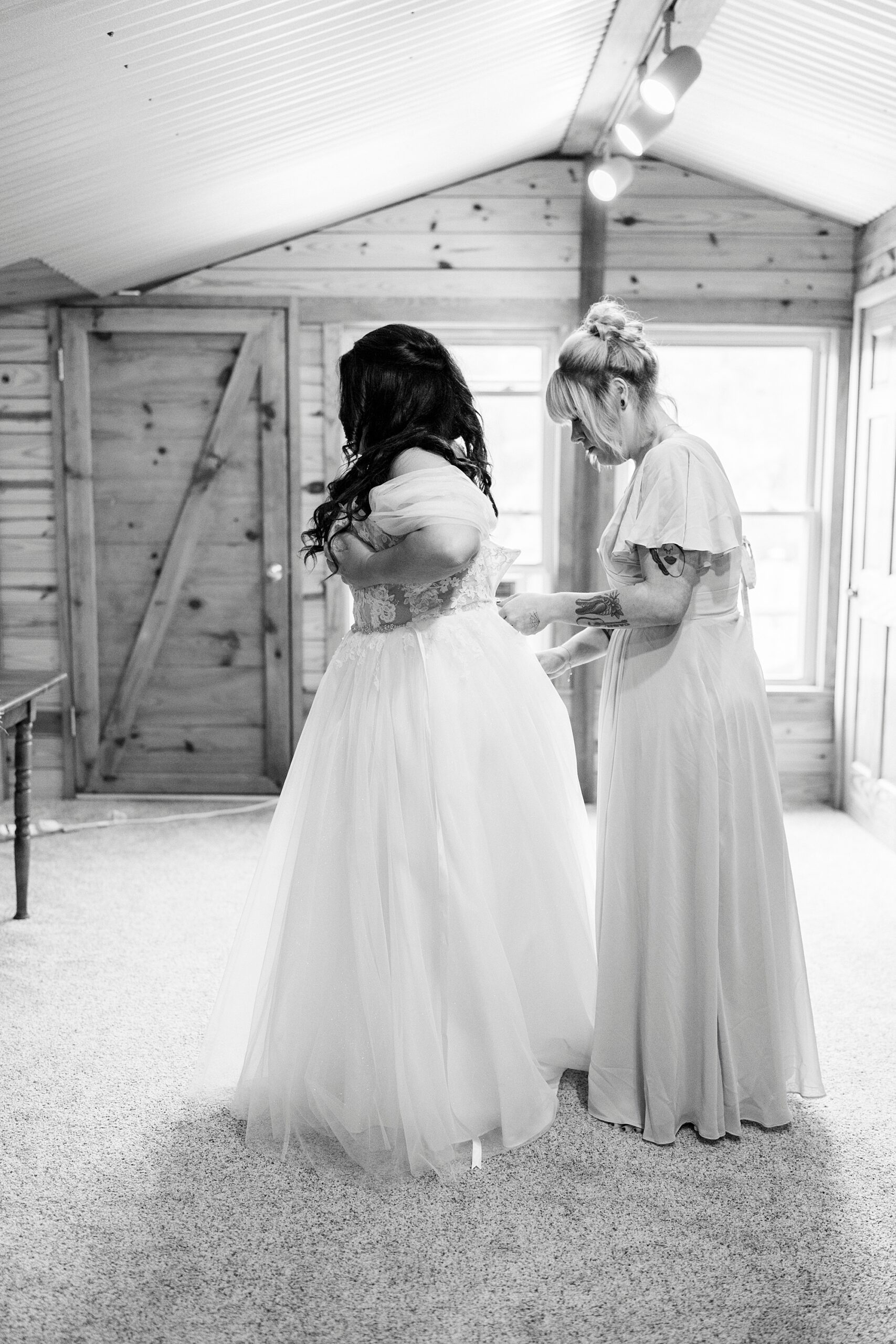mother helps bride into wedding dress in suite at Danner Farms