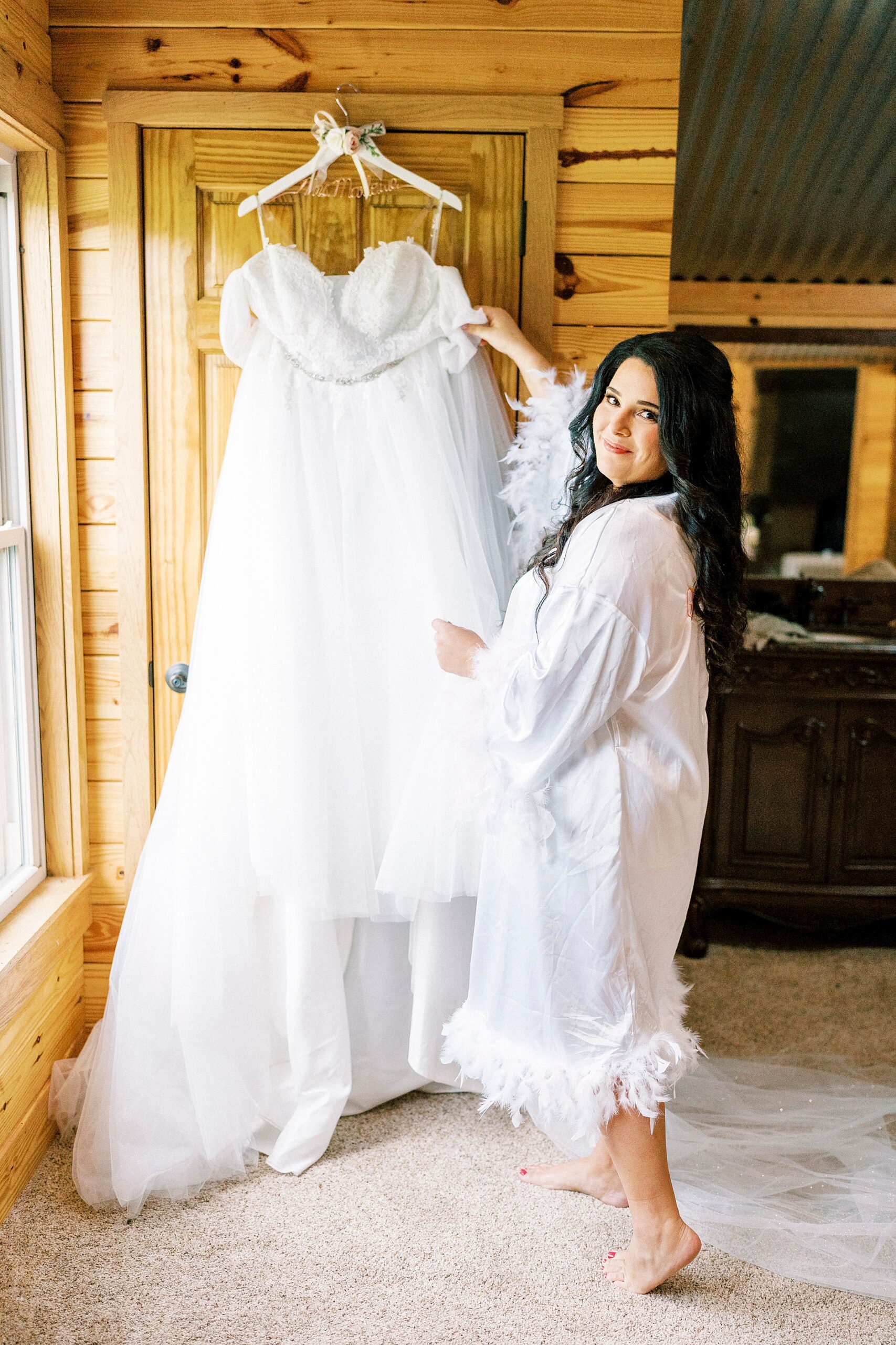 bride hangs wedding dress on wall inside Danner Farms