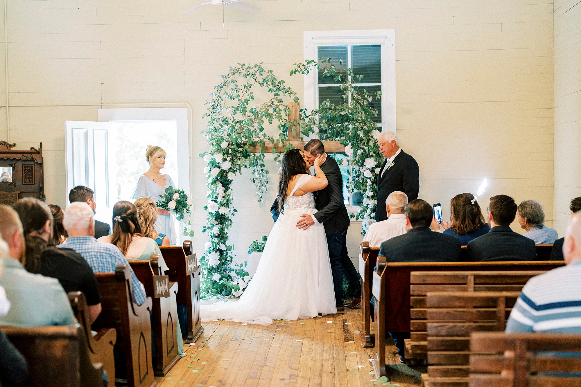 bride and groom kiss during wedding ceremony at Troutman Historical Cemetery chapel