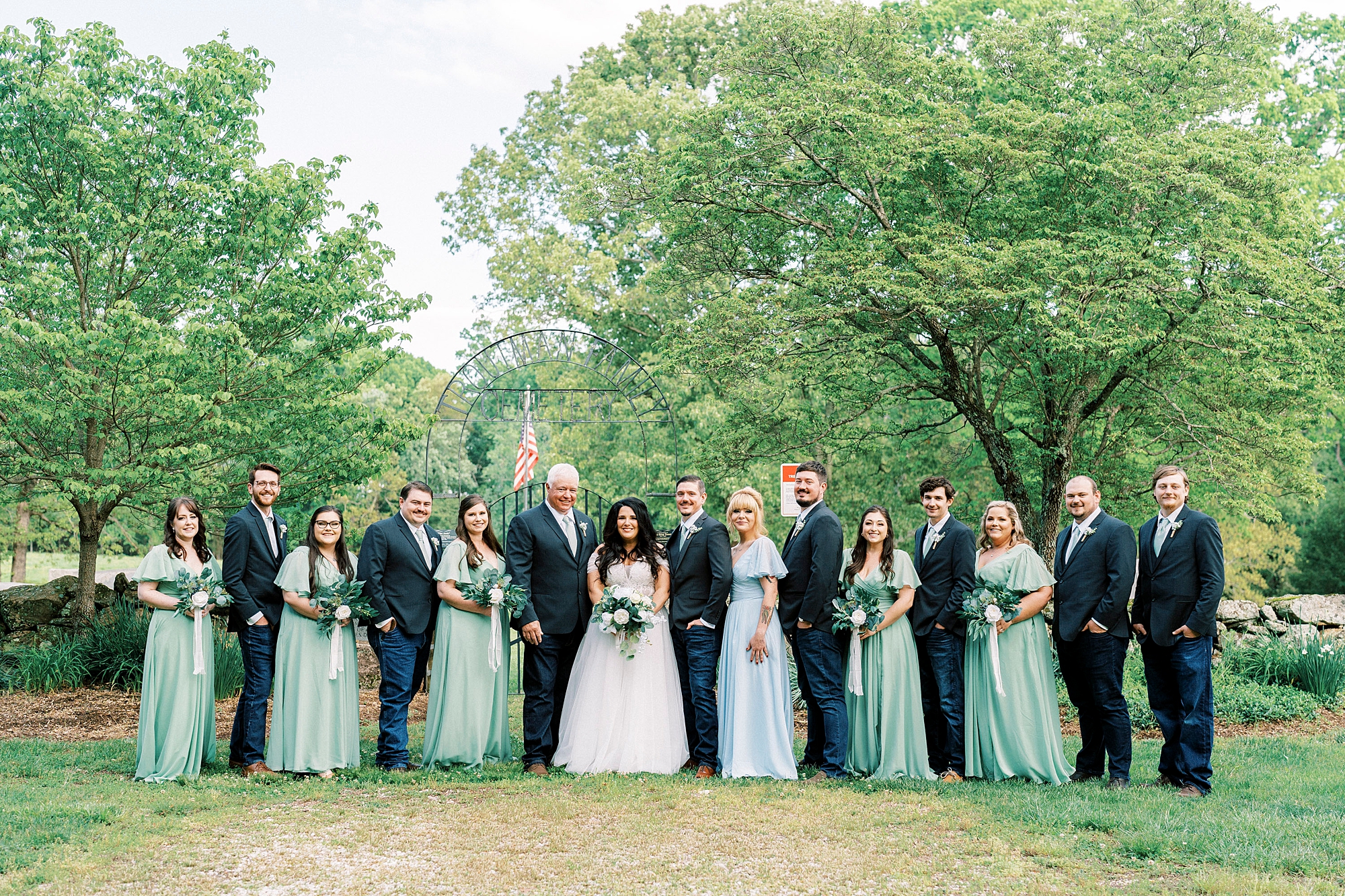 newlyweds stand with wedding party in mint and navy attire
